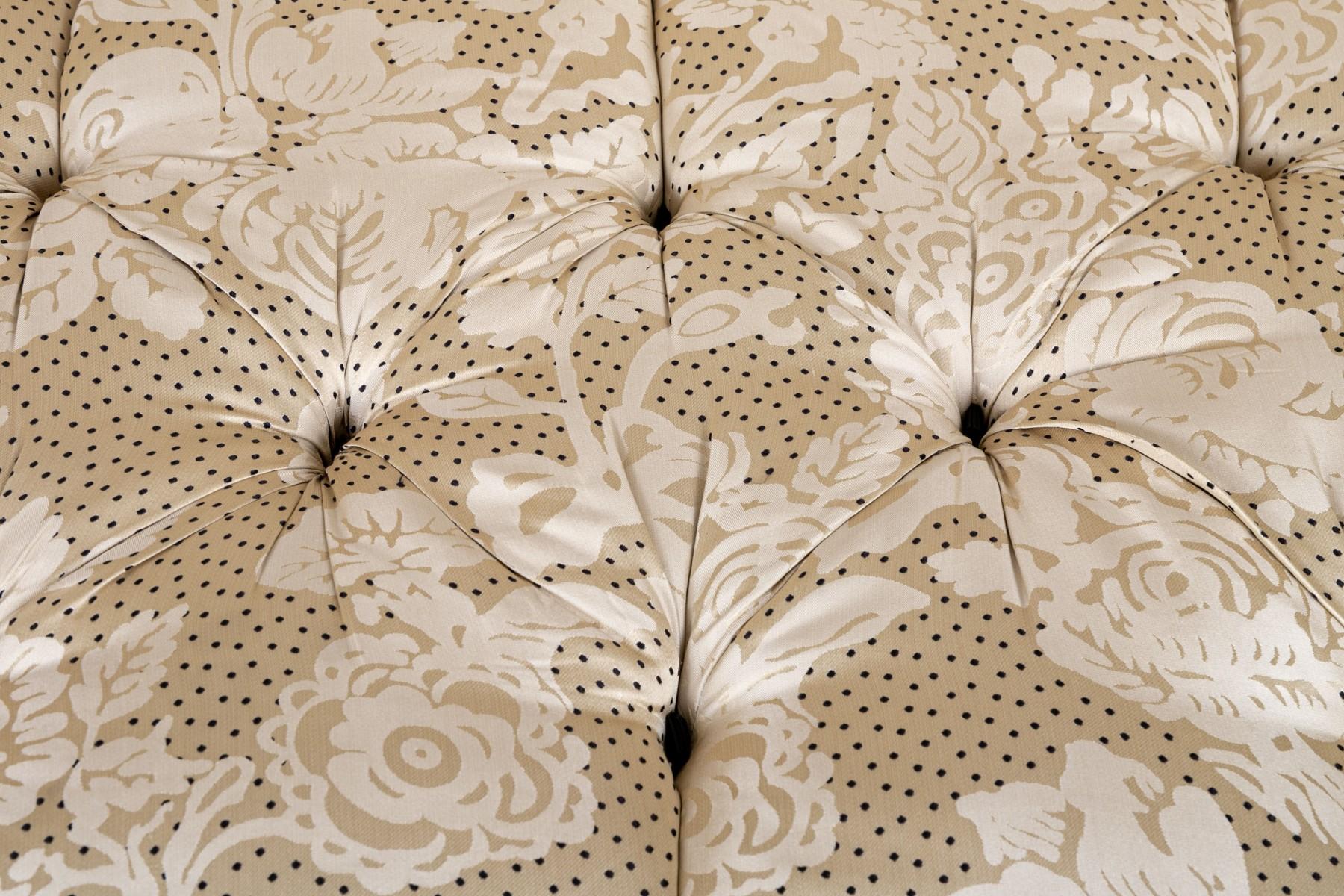 Dieses getuftete Vintage-Sofa strahlt klassische Hollywood-Regency-Eleganz aus, mit einer geschwungenen Rückenlehne, gerollten Armlehnen und tiefen Knopftuftings. Er ist mit luxuriöser Seide und einem kunstvollen Damastmuster gepolstert und hat