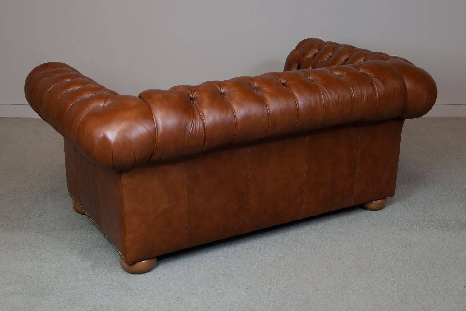 Vintage tufted leather chesterfield sofa. Wooden base.