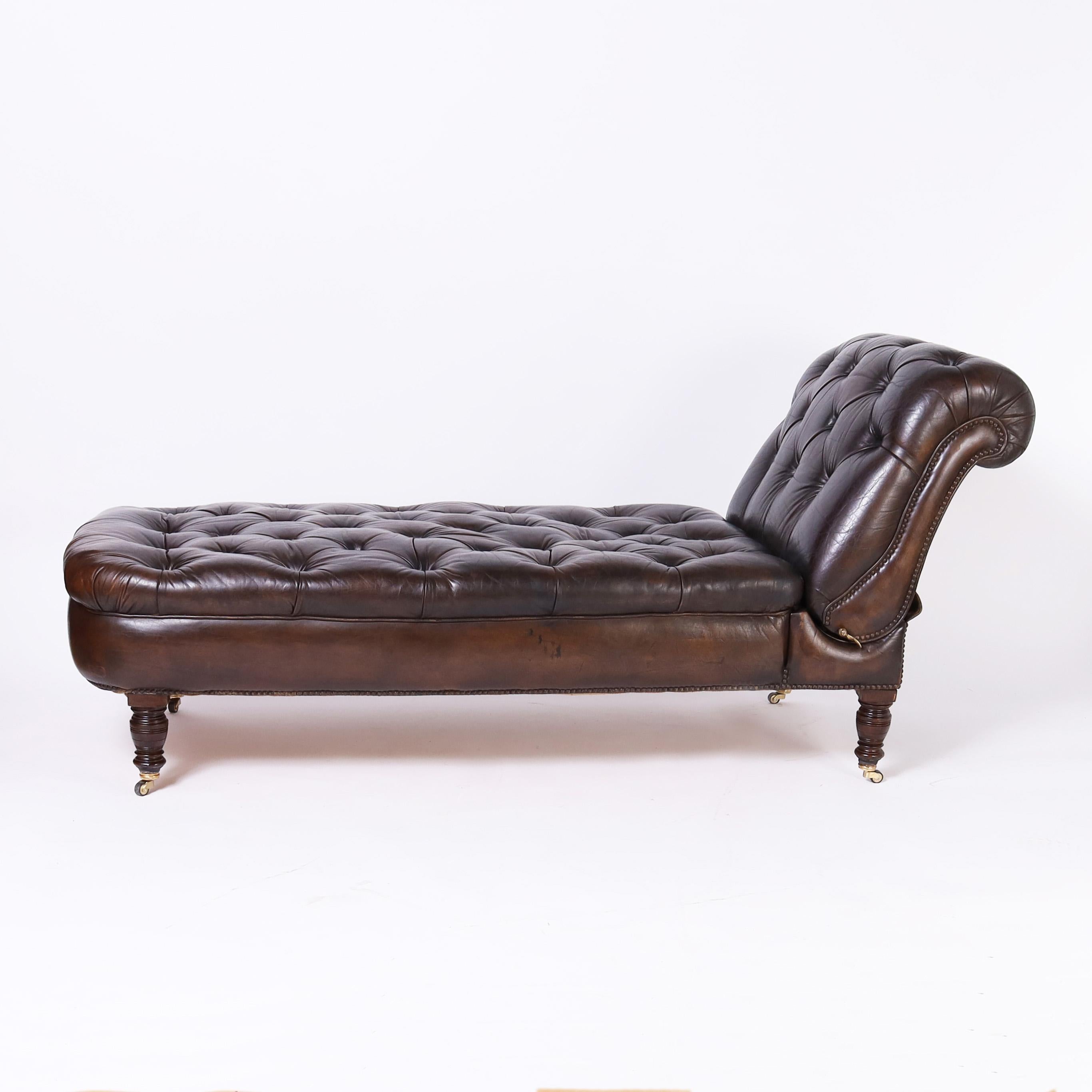 Handsome British Colonial style chaise lounge with tufted leather upholstery featuring an adjustable reclining back, brass tacks and turned legs with brass casters.

H: 35 W: 70 D: 27
Extended width: 78
Seat: 18
