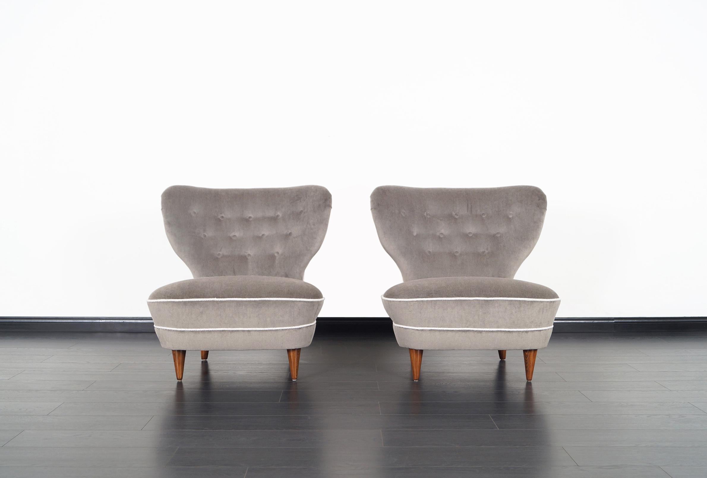 Stunning pair of vintage wingback lounge chairs designed and manufactured in the United States, circa 1950s. These chairs show clean lines and great craftsmanship. Newly upholstered in mohair with tufted details on the backrest.