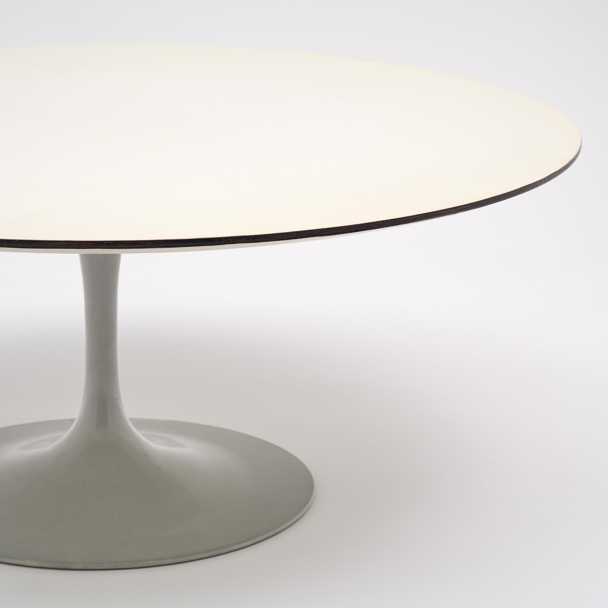 Coffee table from France in the manner of Knoll with a circular top finished with a white laminated surface. The base is a metal tulip shaped base with a white finish as well. This piece is in very nice vintage condition with only minor surface wear