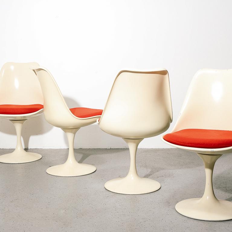 Vintage white fiberglass dining chairs designed after Eero Saarinen for Knoll. Offered here with original red cushions. Sold as a set of 4.