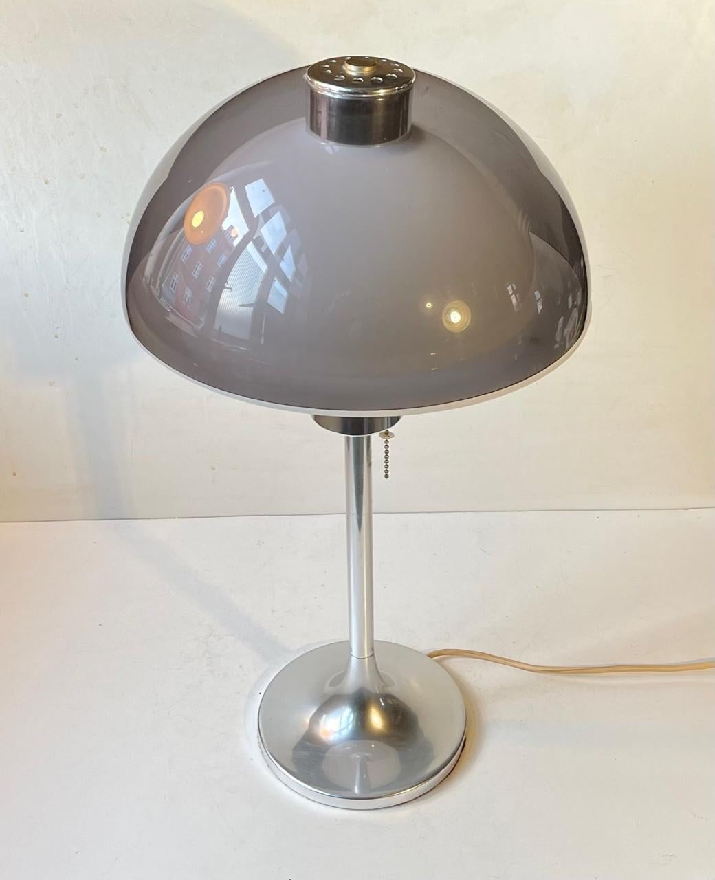 A stylish space age table or desk lamp designed in 1966 by Robert Welch and manufactured by Lumitron in England. Inner plastic diffuser in white with outer dome of grey transparent acrylic. It features a base in polished aluminium and a string on/of
