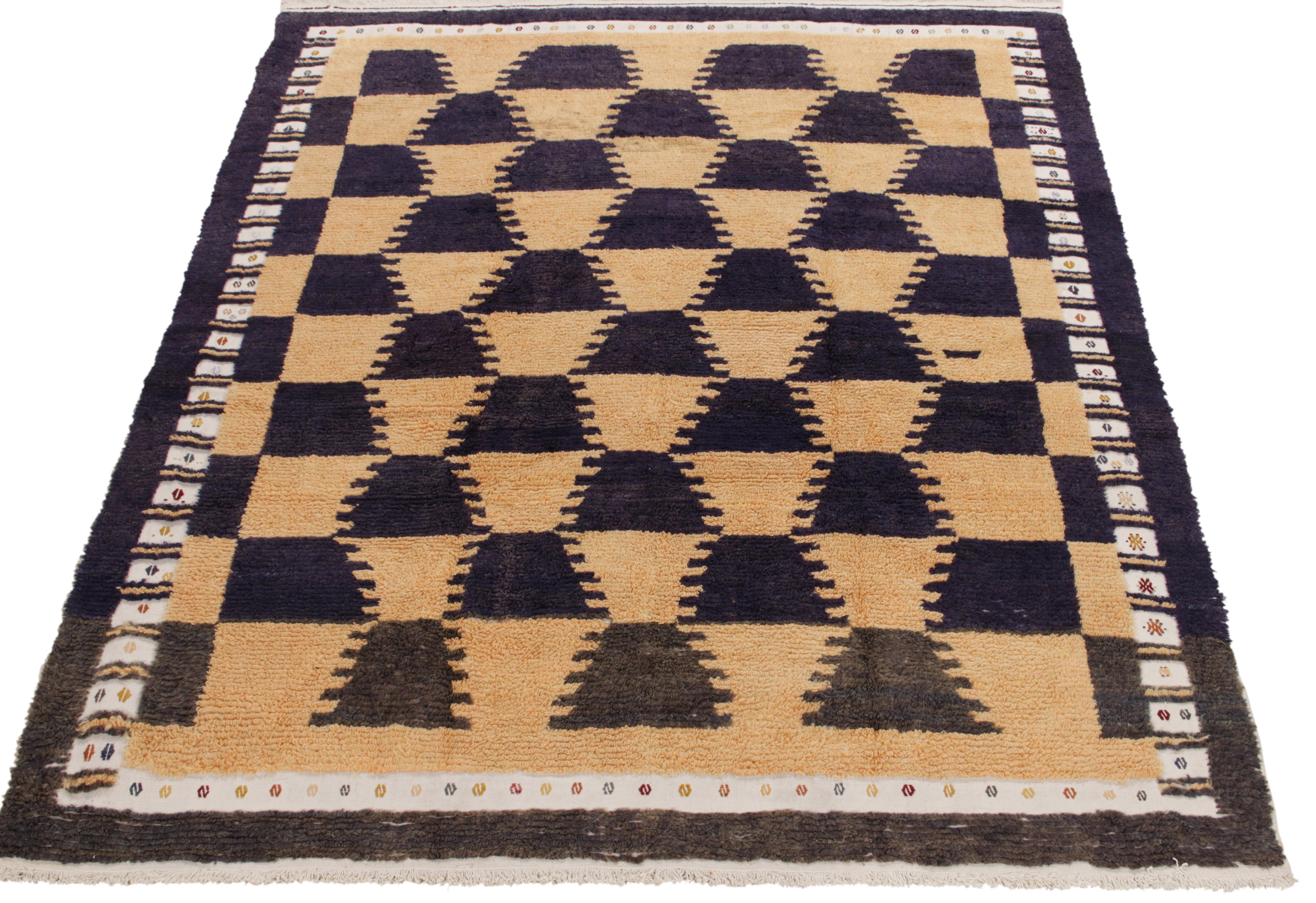 A spectacle of fine craftsmanship, this Tulu rug of the 1950s from our antique & vintage collection unveils sharp geometry in tribal designs bracing beige, midnight blue & grisailles black tones. Connoisseurs may observe a delicate white border