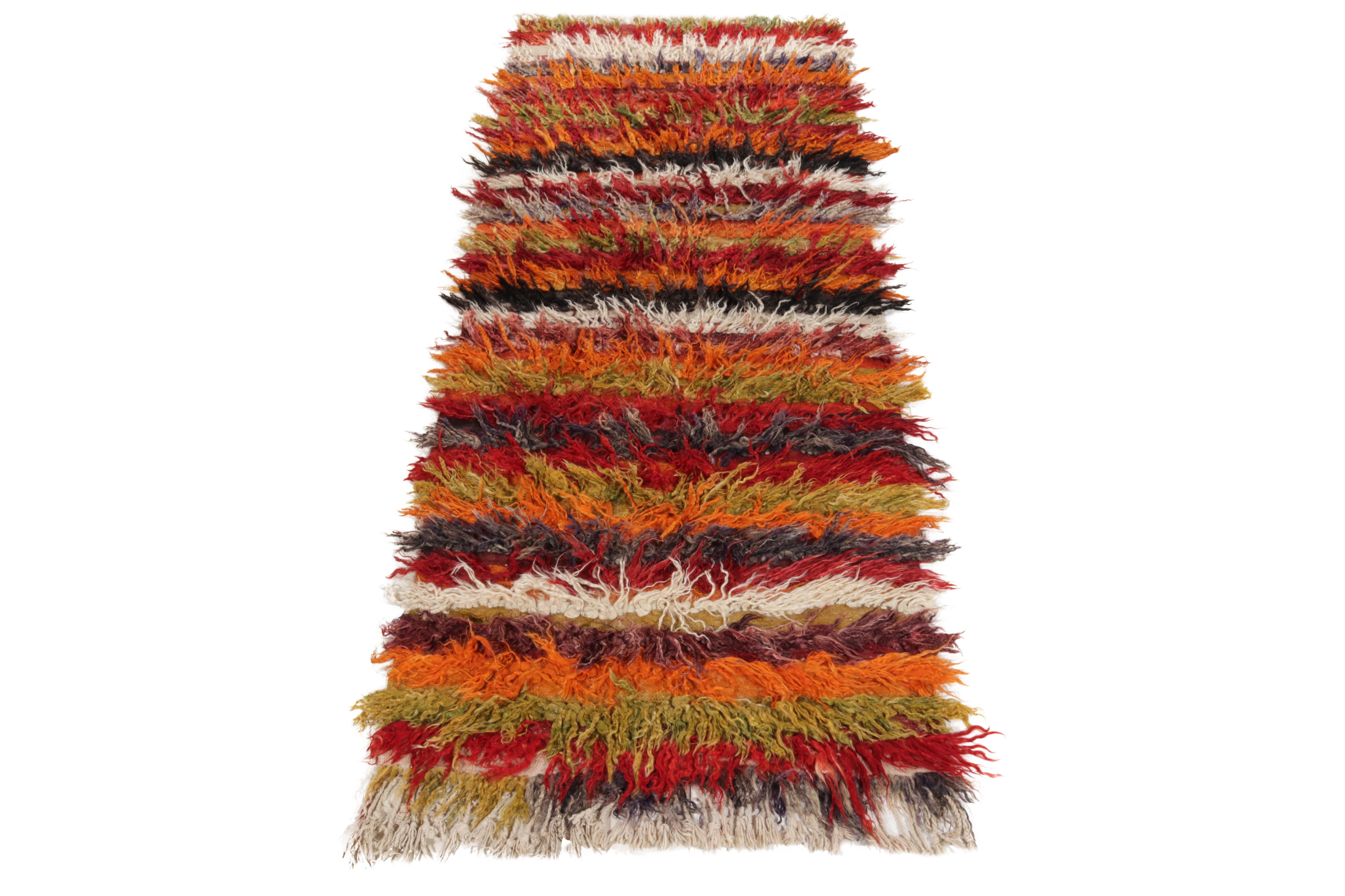 Hand-knotted in wool circa 1950-1960, this 4x10 vintage rug enjoys a delicious high pile in bold red, lavender, tangerine & grass green playing joyfully with Tulu aesthetics of the mid century era. Thriving in pristine condition, a textural piece