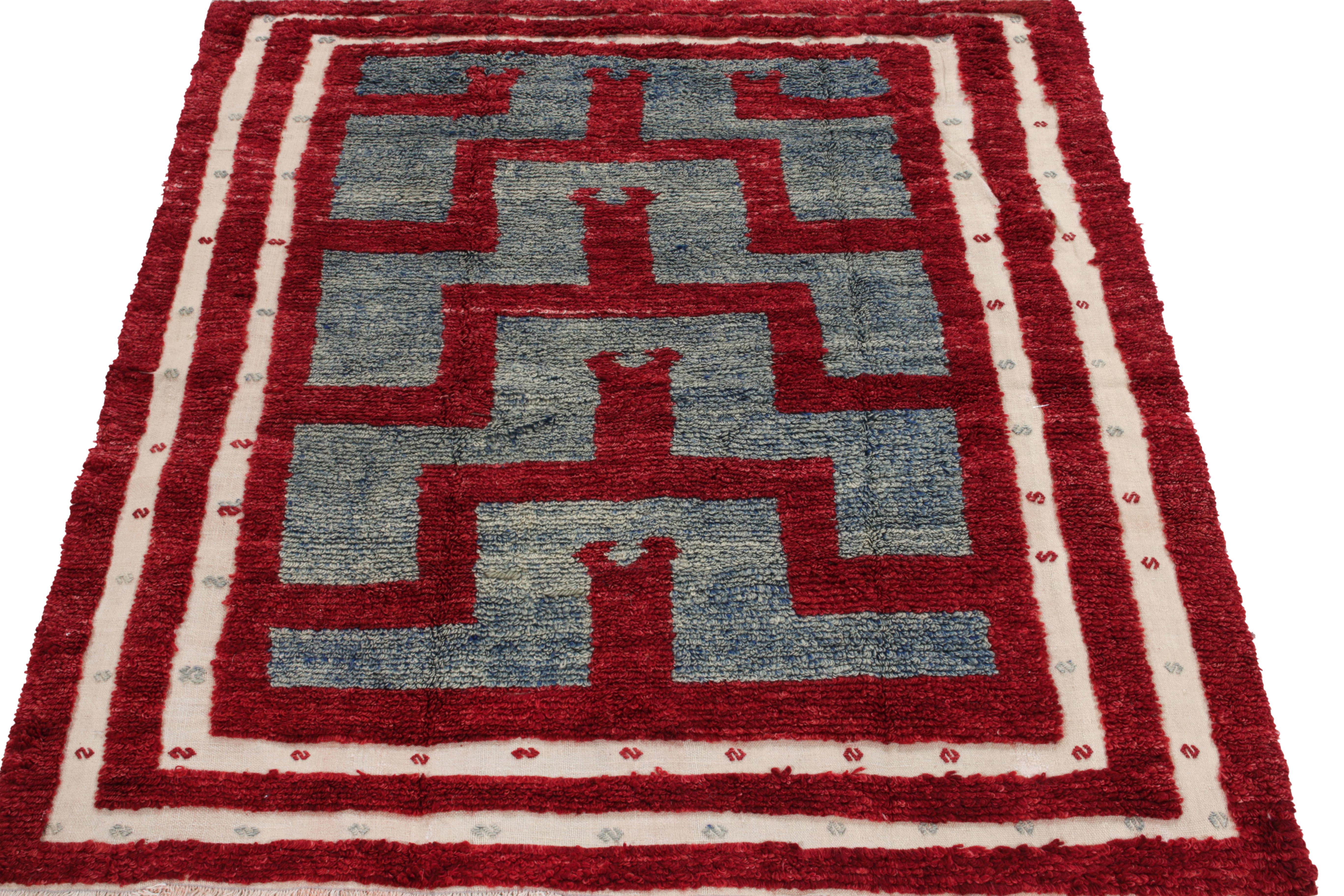A spectacle of fine craftsmanship, this vintage 5x6 Tulu rug of the 1950s from our Antique & Vintage collection unveils sharp geometry in tribal designs bracing scarlet red & light blue tones. Connoisseurs may observe a delicate white border