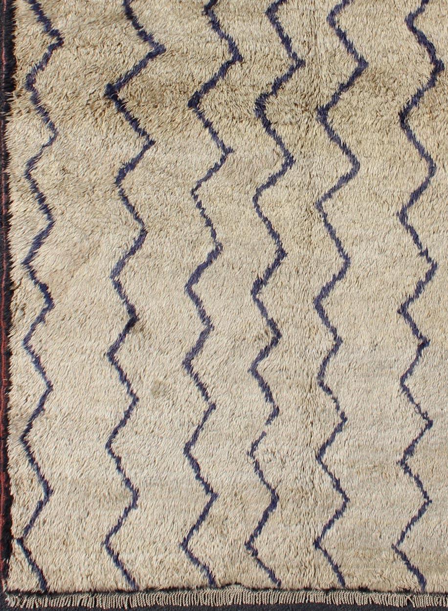Dieser atemberaubende zweifarbige Tulu-Teppich zeigt dunkelblaue Linien auf einem sandfarbenen/taupefarbenen Hintergrund. Der Flor ist üppig und von sehr hoher Wollqualität. Das schlichte und doch exquisite Design macht diesen Teppich zu einem