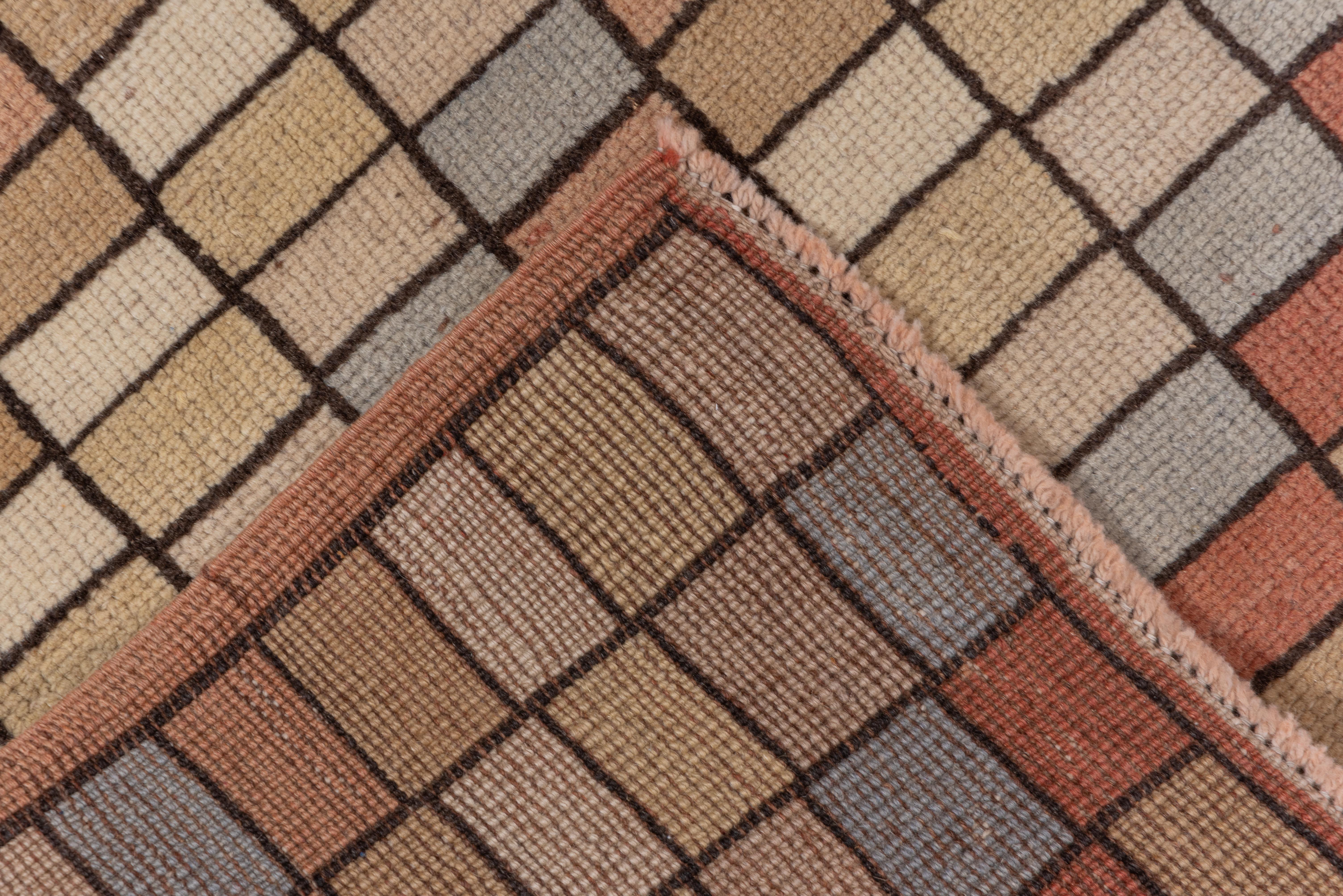This vintage Tulu runner showcases a playful mosaic-style grid pattern composed of soft pastel squares in peach, ivory, sand, and slate blue, outlined in a fine brown linear weave. The irregular rhythm of the tiles adds a sense of movement and