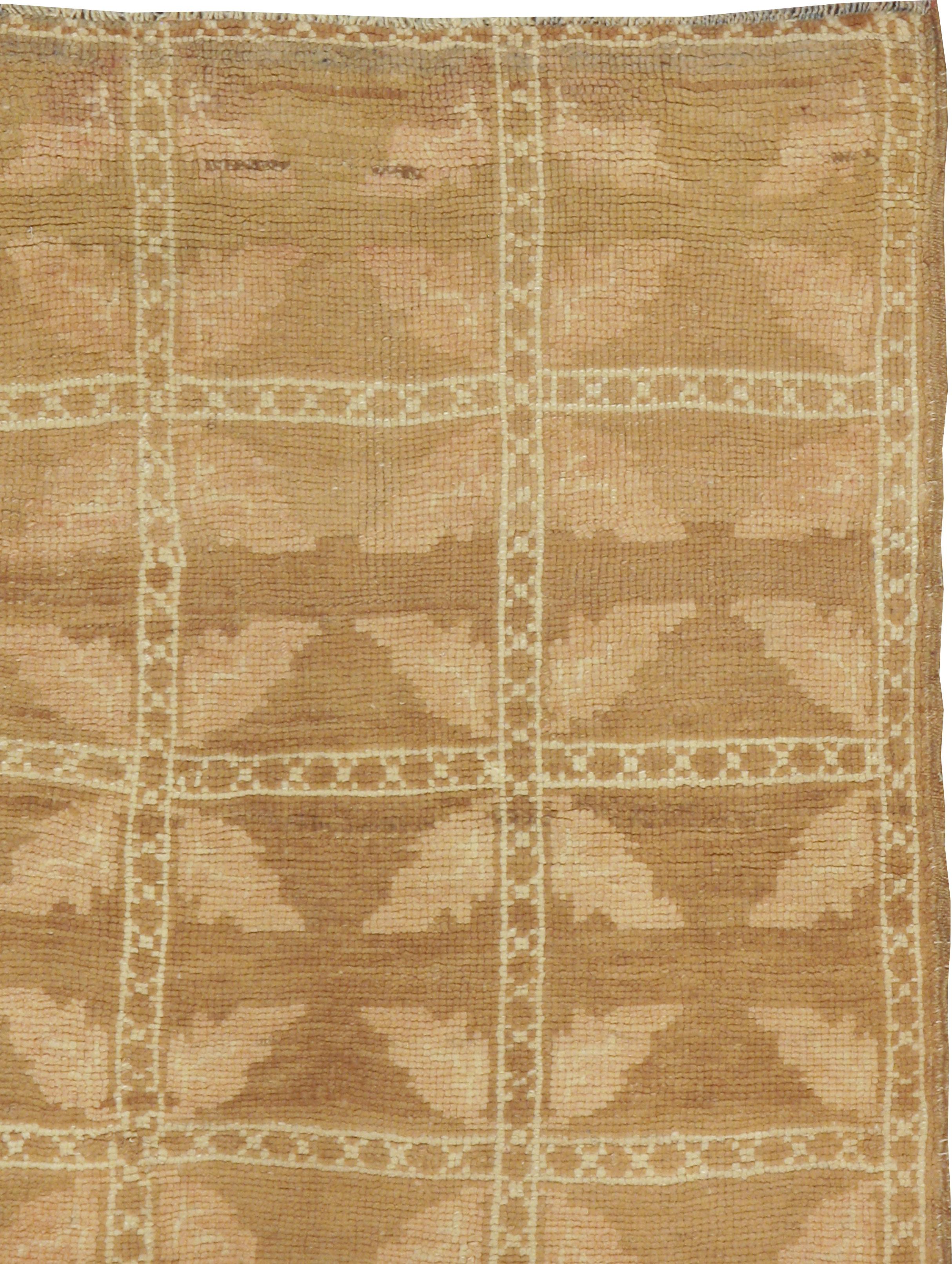 A vintage Turkish Anatolian rug from the mid-20th century. A square brown grid of five squares by eight displays a leafy Maltese cross in each panel. The colors are soft: rust-brown tan and old ivory. The skinny border is an extension of the