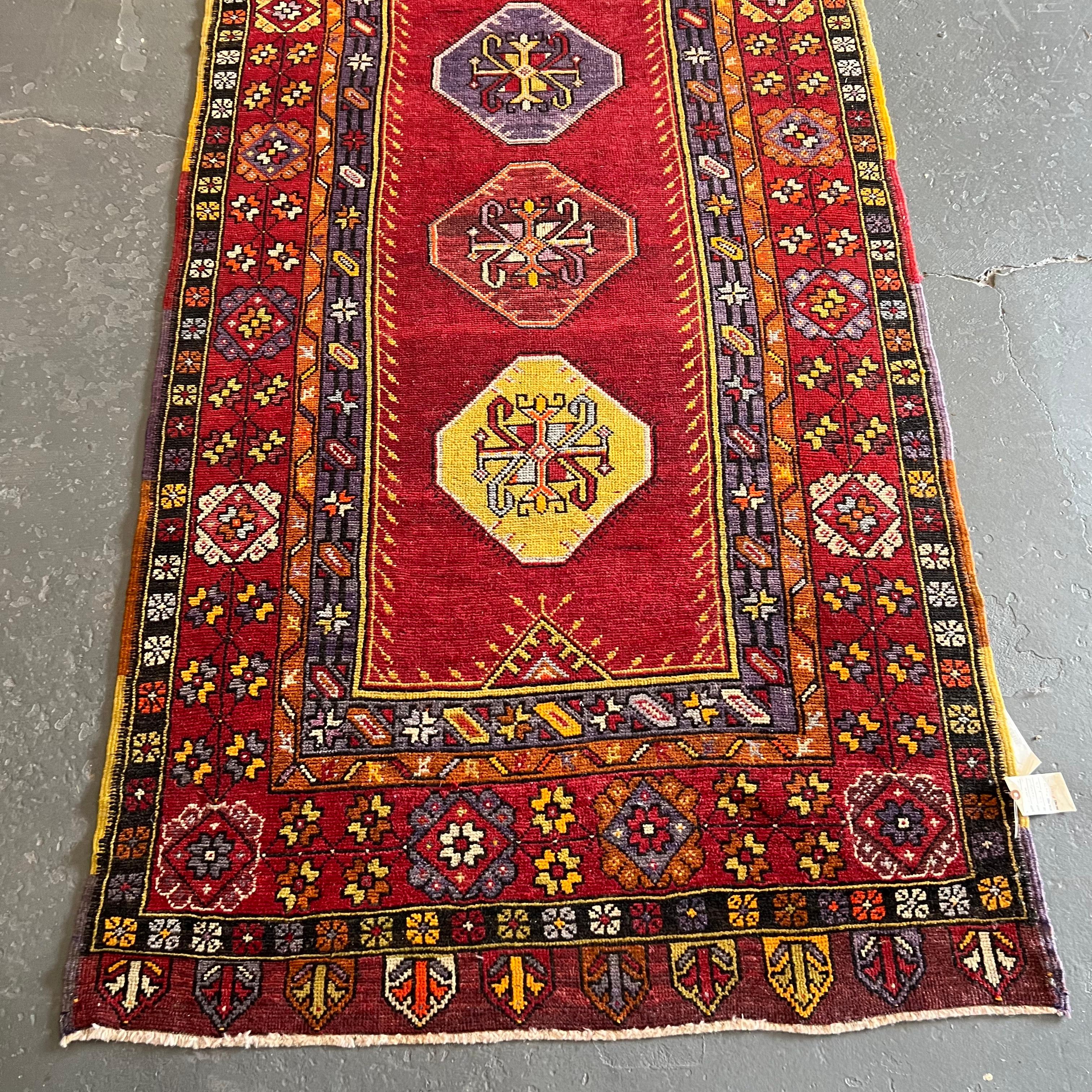 Vintage Turkish Anatolian rug with red, purple, yellow and orange hues.