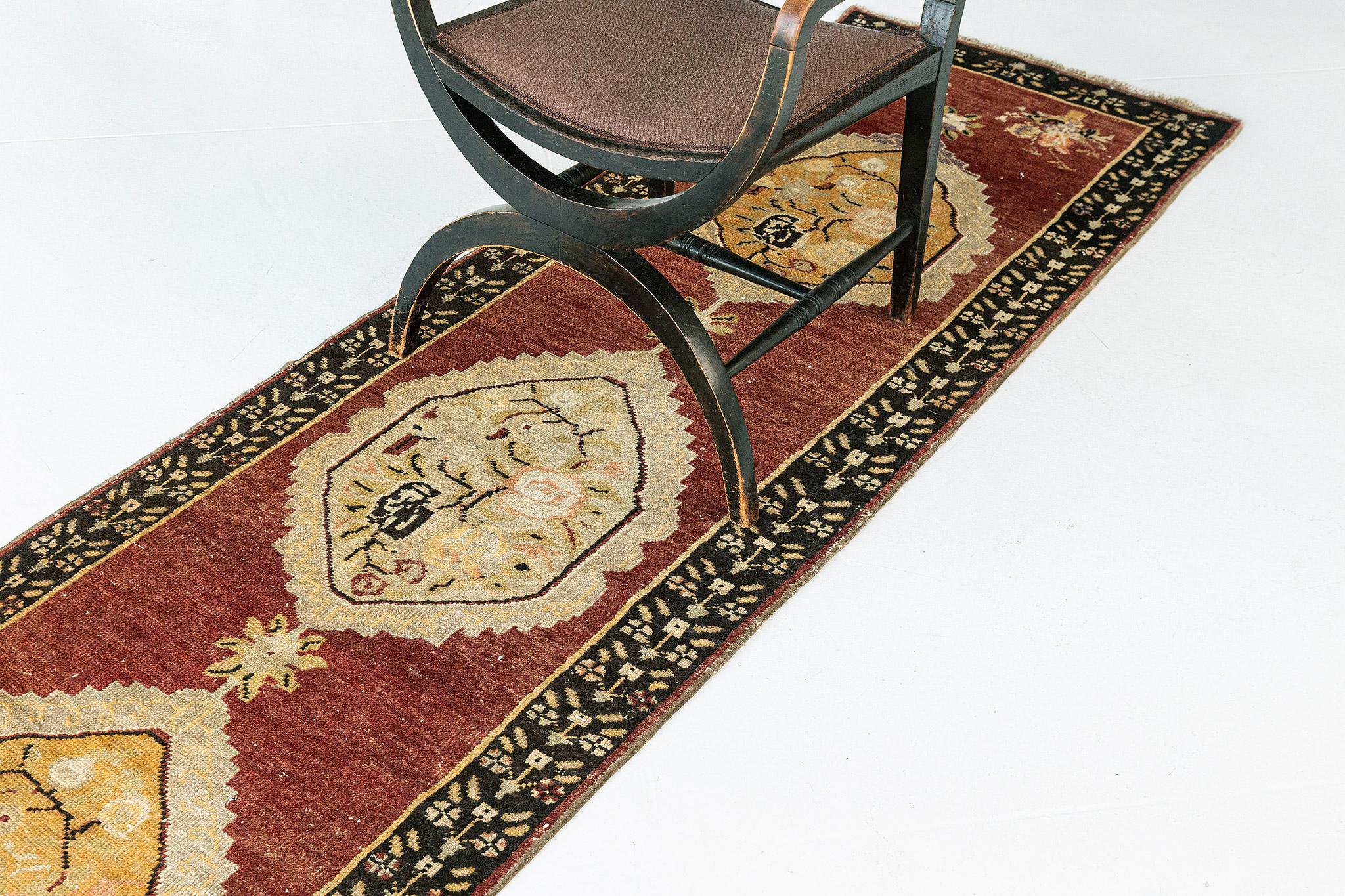 With its impressive design, rich detailing, and mesmerizing well-balanced symmetry, this vintage Turkish Anatolian runner would bring a sense of classic sophistication to nearly any space. The abrashed fire brick colored field features an three