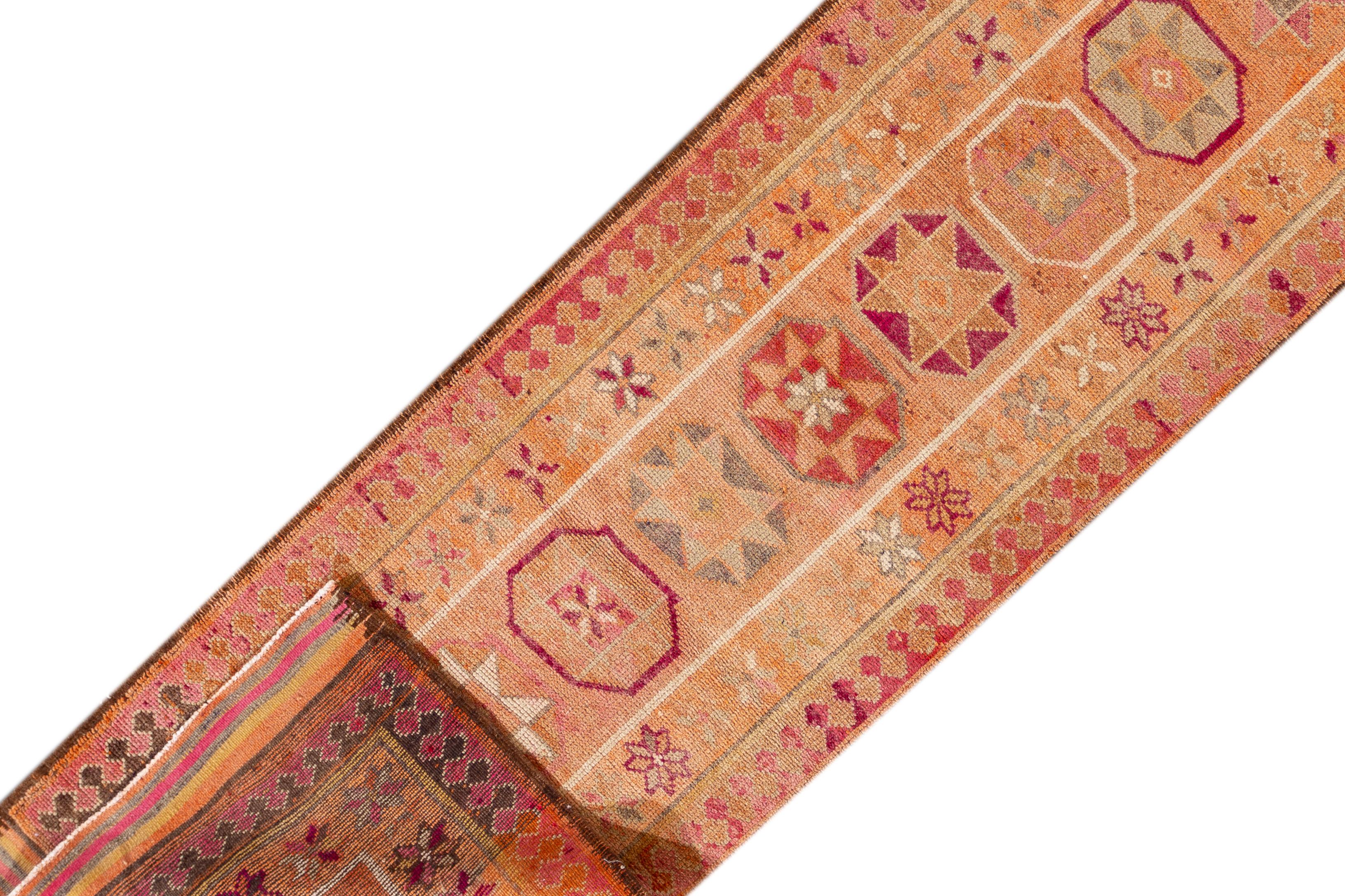 A 20th century vintage Turkish Anatolian runner rug with an all-over orange geometric motif. This rug measures at 3'2