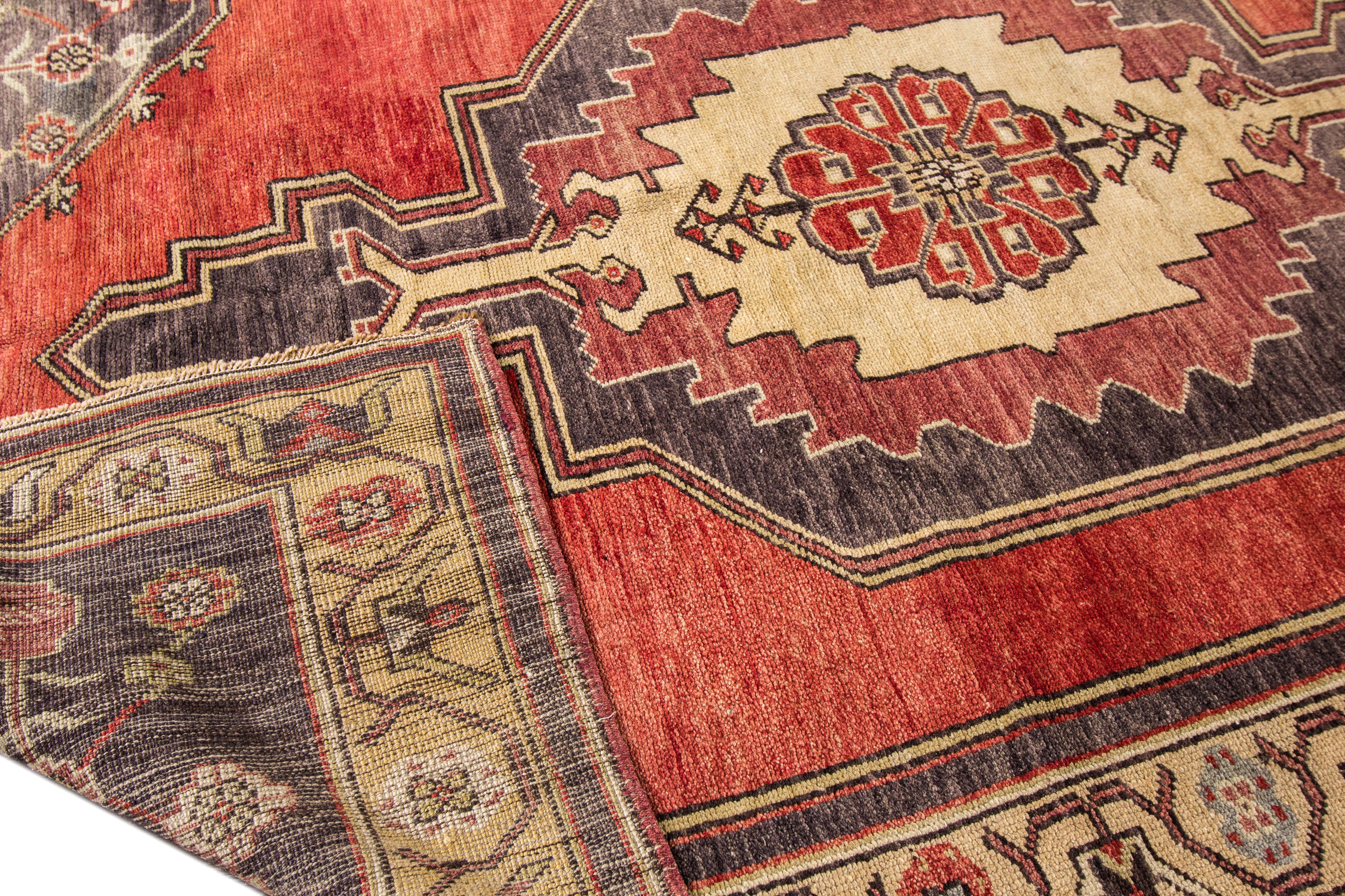 A 1950s vintage hand knotted wool Turkish Anatolian runner rug with a rust-red field and medallion design. This rug measures 5'0