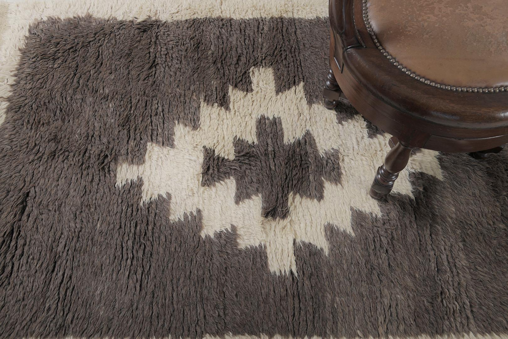 Featuring a gorgeous wool shag of this vintage Turkish Anatolian Tulu that showcases a muted and captivating earthy tones of ivory and cedar brown. This remarkable rug displays a serrated lozenge medallion gloriously accented in the plush field.
