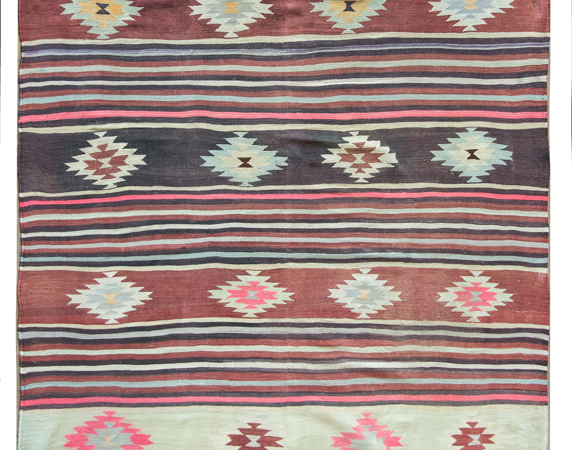 A wonderful vintage Turkish Bergama kilim rug with a striped pattern of alternating thin violet, cranberry, cream, and gold colored stripes, with wider cream colored stripes with diamond medallions.