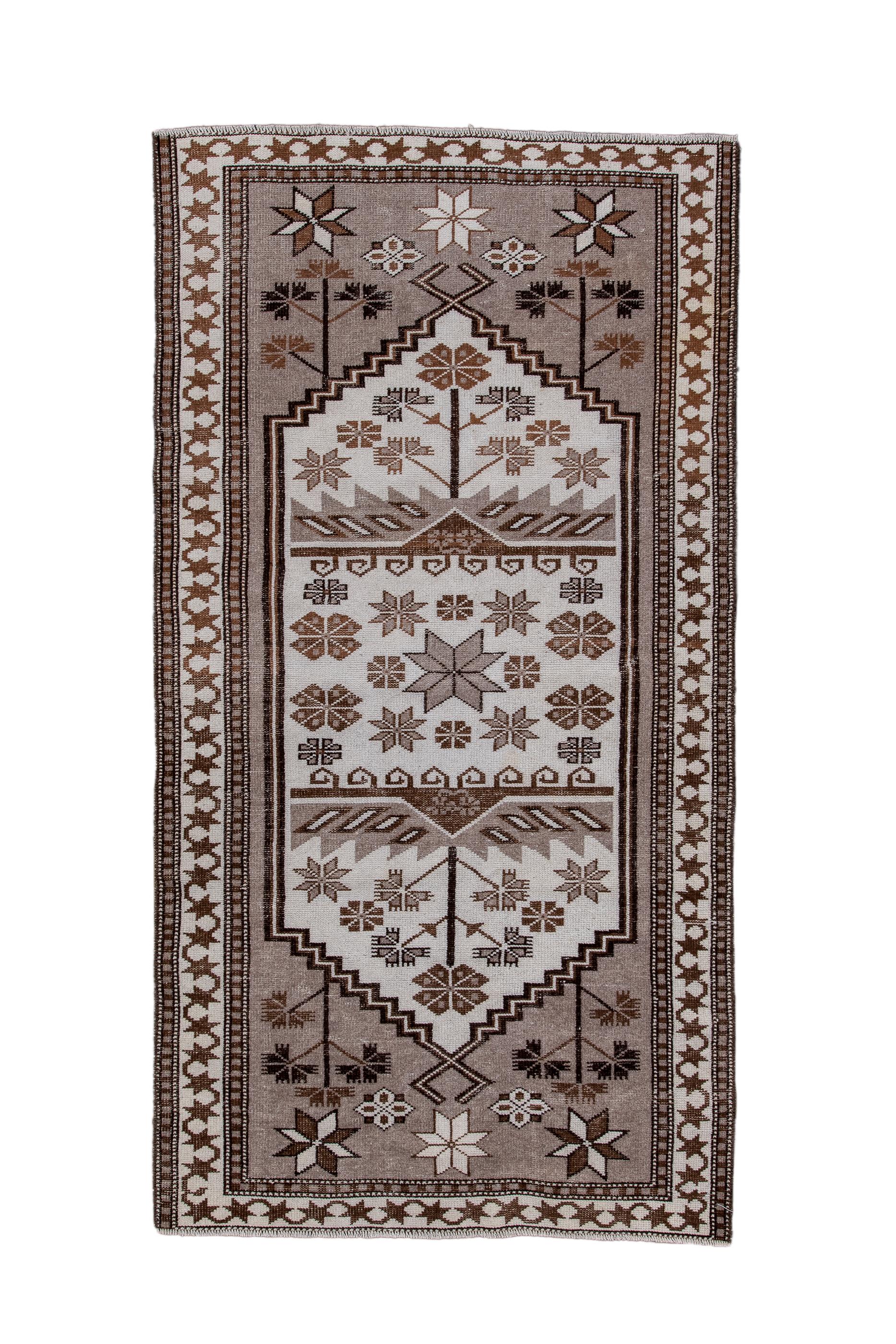 This Bergama from northwest Turkey shows  a grey green field with a tall, central, stepped hexagonal ecru panel decorated with stars, rosettes, carnations, and two broad, sharp-leaf brackets. Stars and carnation plants ornament the corners. Flip