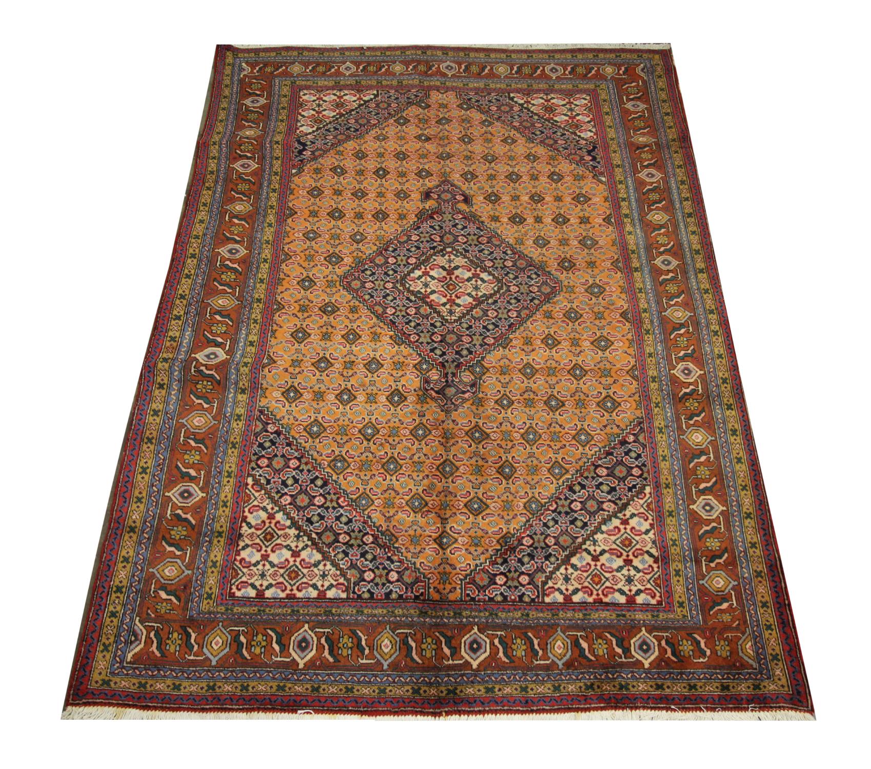 This vintage wool rug is a fine Turkish carpet woven with a symmetrical motif design. Featuring a rust gold background and accents of blue, cream, brown and red that make up the intricate medallions and geometric patterns. The distinctive character