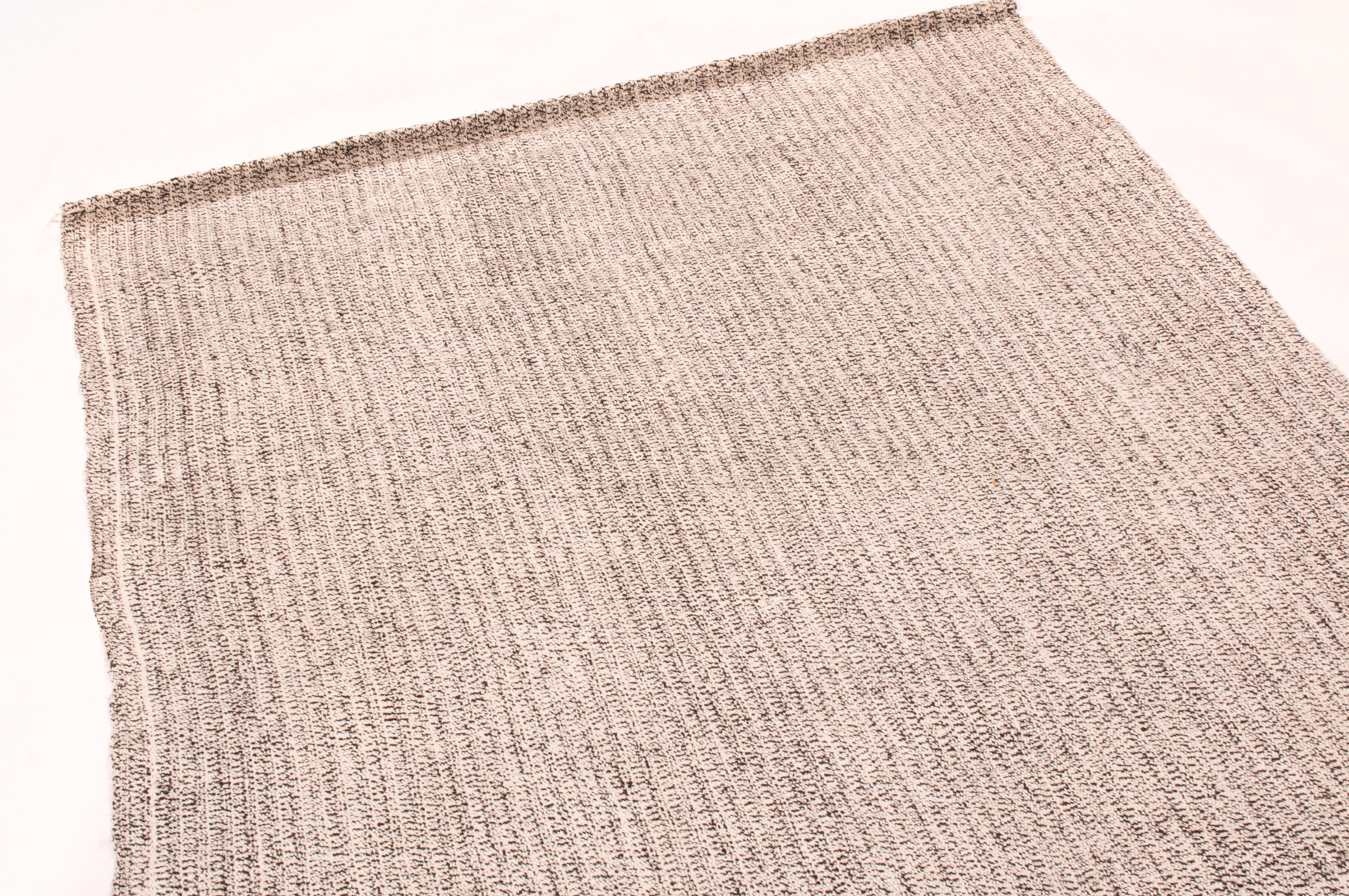 Originaire de Turquie en 1980, ce tapis kilim vintage en laine est tissé à plat dans une laine de haute qualité avec un abrash contemporain et subtil de couleurs industrielles grises et argentées.