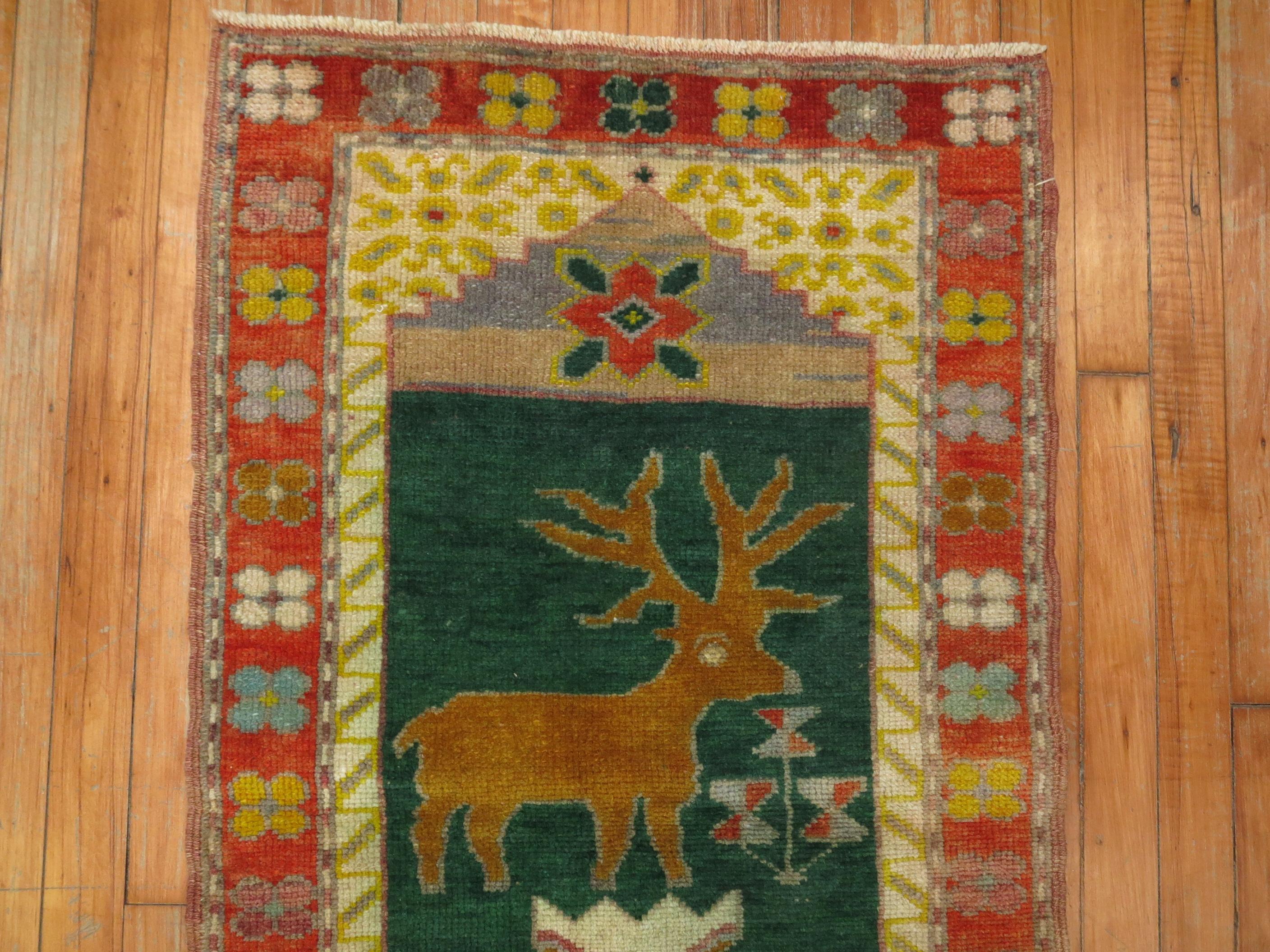 A vintage Turkish Pictorial rug depicting a deer on a forest green ground.

 
