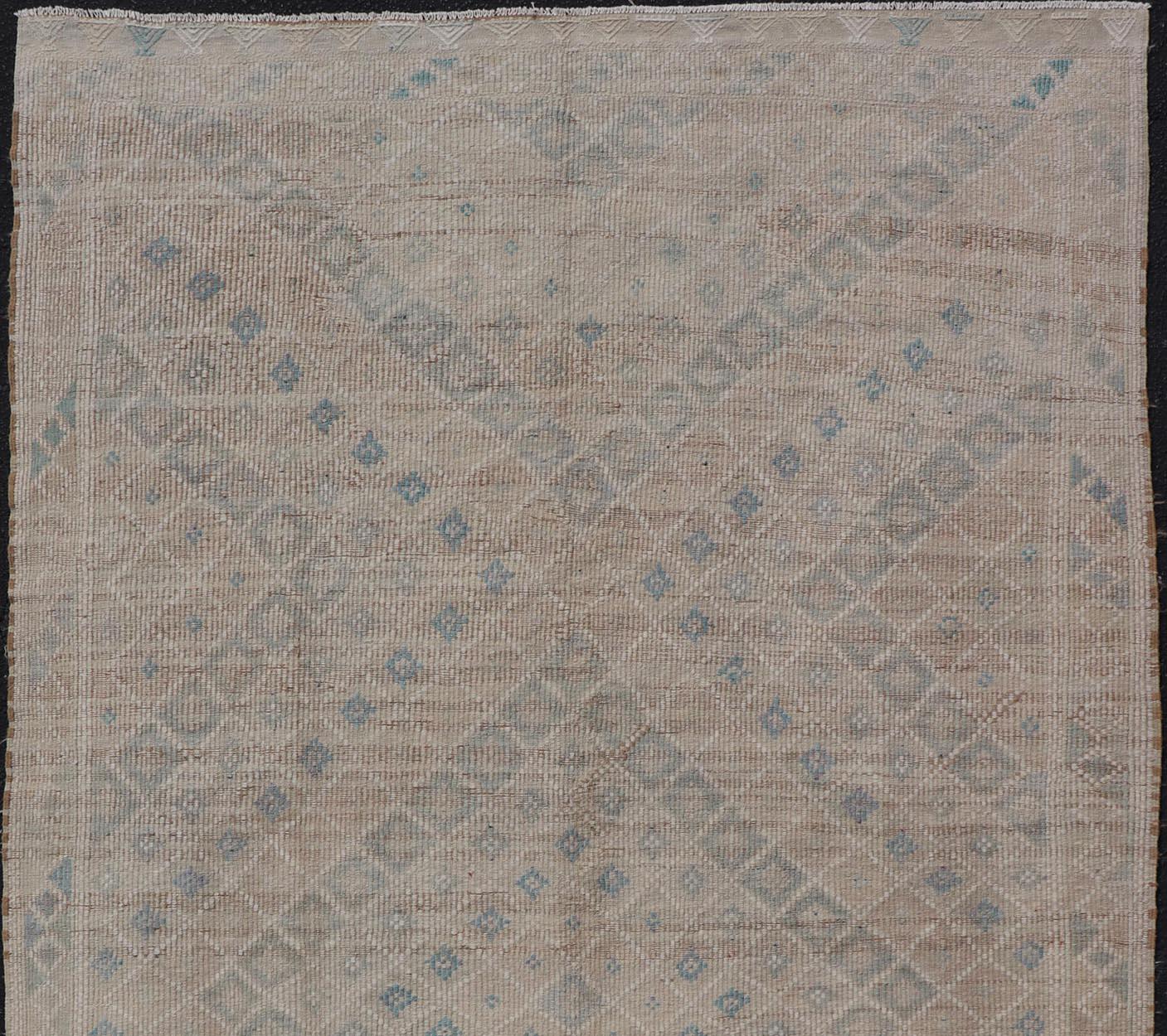 Measures: 6'1 x 10'1 

This hand-woven Kilim features muted shades of taupe, light blue, light green, camel, and small accent details in cream. The all-over design displays a geometric diamond design, each lightly stylized with an accent color