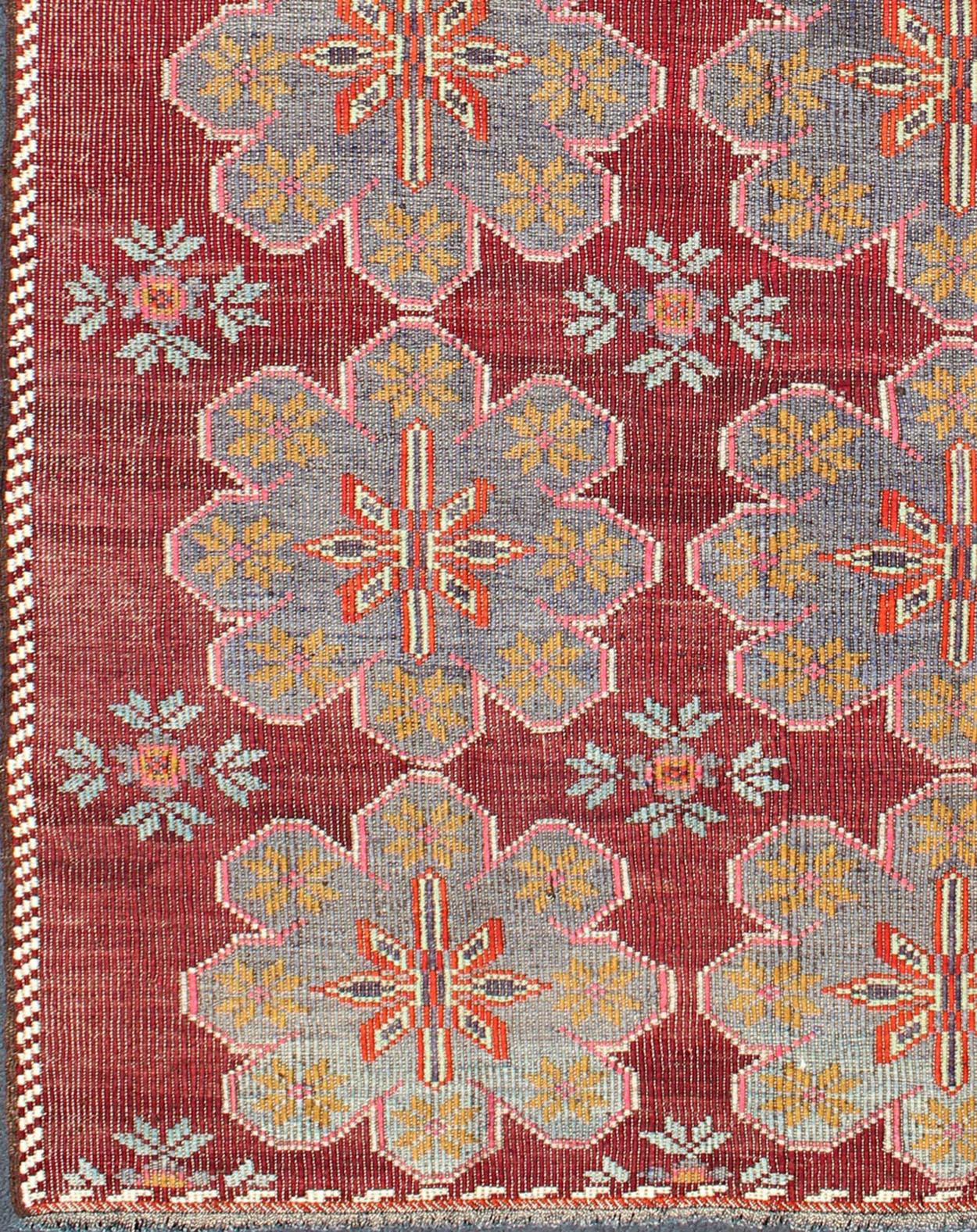 Vintage Turkish Embroidered Kilim Rug in Wine Red, Steel Blue, Pink and Orange.
Featuring tribal flowers with a spotted and speckled assortment of geometric elements, this vintage Turkish Kilim showcases an array of rich and colorful tones. Colors