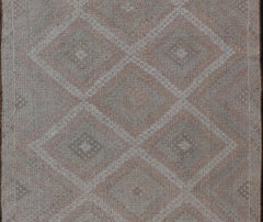 Tapis turc vintage brodé avec un motif géométrique en forme de losange et des couleurs douces