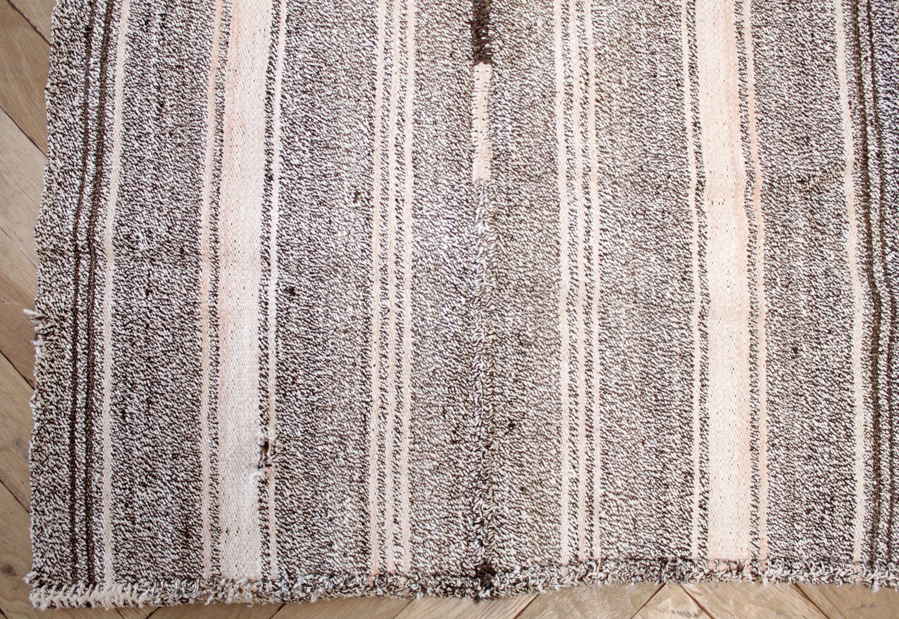 Türkischer Teppich im Vintage-Stil in Braun mit weißer Webart und cremeweißen Streifen, mit dunkelbraunen Streifen und dezenten rosafarbenen Streifentönen.
Flachgewebe, Wolle und Ziegenhaar machen sie extrem haltbar und eignen sich hervorragend für