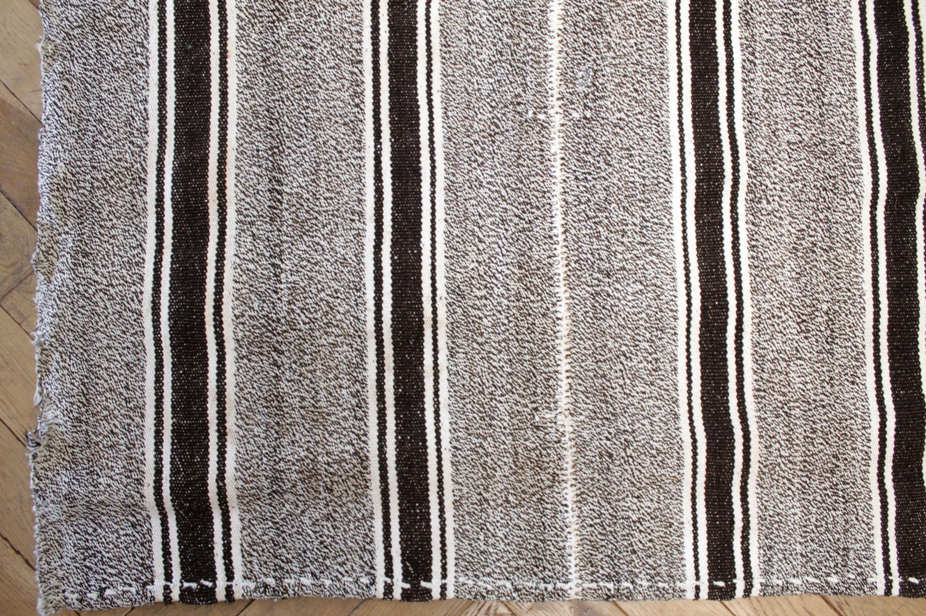 Peyton-Teppich
Türkischer Vintage-Teppich in Braun mit weißer Webart und cremeweißen Streifen, mit dunkelbraunen Streifen.
Flachgewebe, Wolle und Ziegenhaar machen sie extrem haltbar und eignen sich hervorragend für stark frequentierte Bereiche.