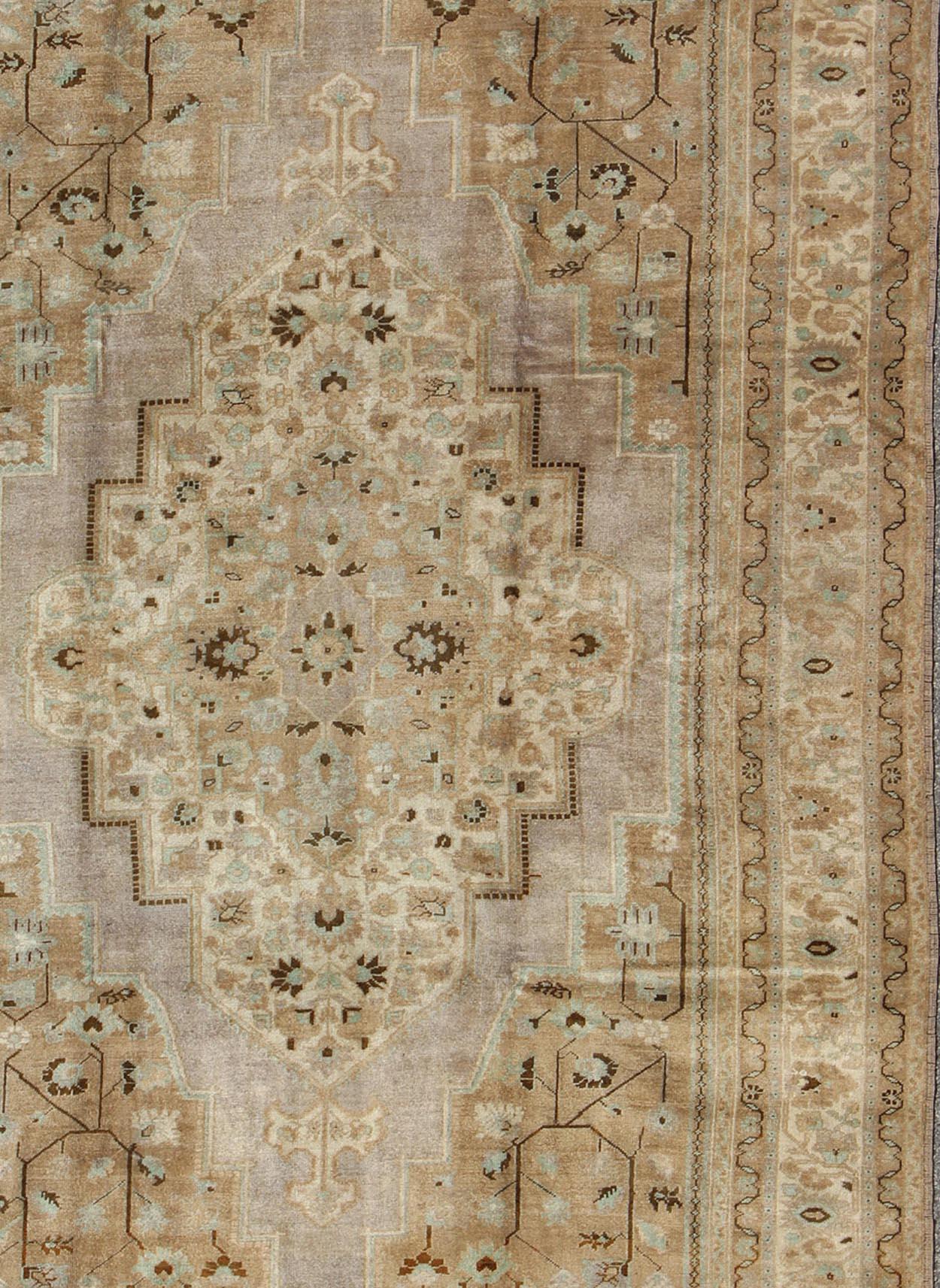 Measures: 7'2 x 11'0

This stunning vintage Turkish Oushak carpet (circa mid-20th century) features a central medallion with floral motifs and subtle sub-geometric elements throughout the medallion, surrounding light lavender field, cornices, and