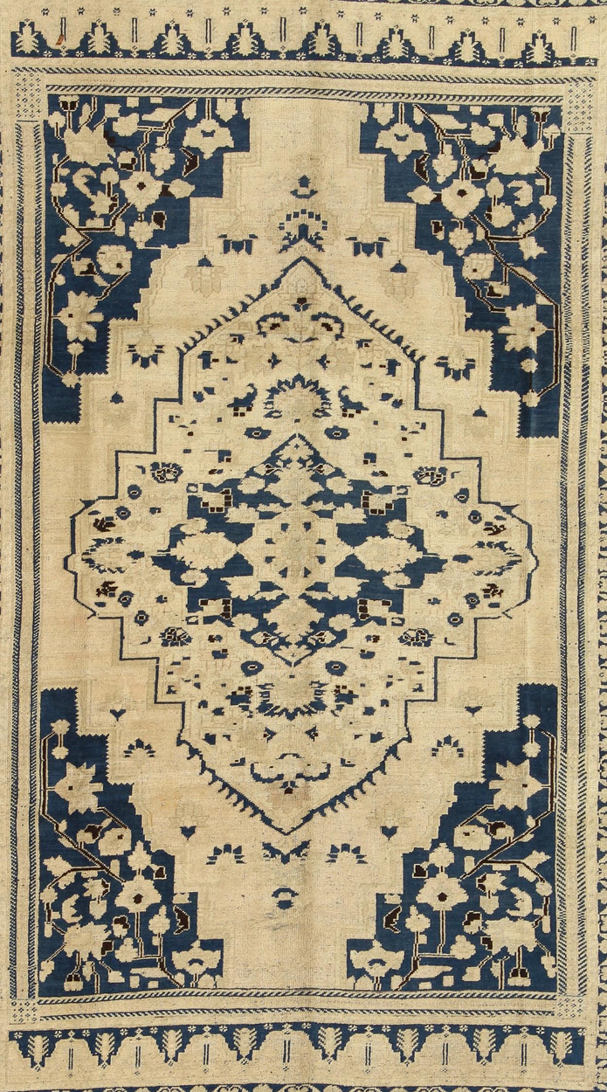 Measures: 7'11 x 10'11

This vintage Oushak features classic Oushak medallion designs, with more contemporary colors. The antique-white field displays a large central diamond medallion, decorated with abstract floral motifs rendered in royal blue.