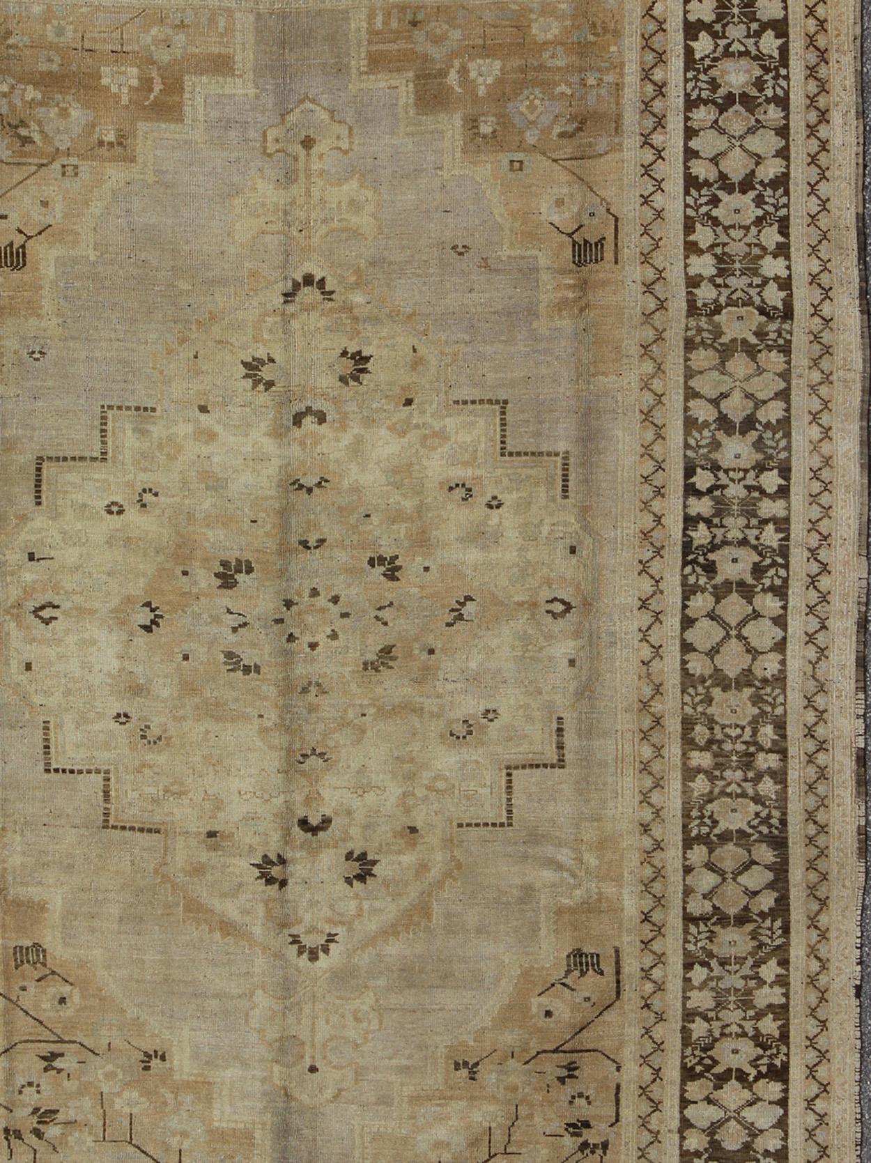 This Vintage Turkish Oushak, from 1940s Turkey, featuring a chocolate brown border with connecting flower and vines. The sandy field combines taupe and tan with dark brown and antique-white in a large central medallion and floral cornices.