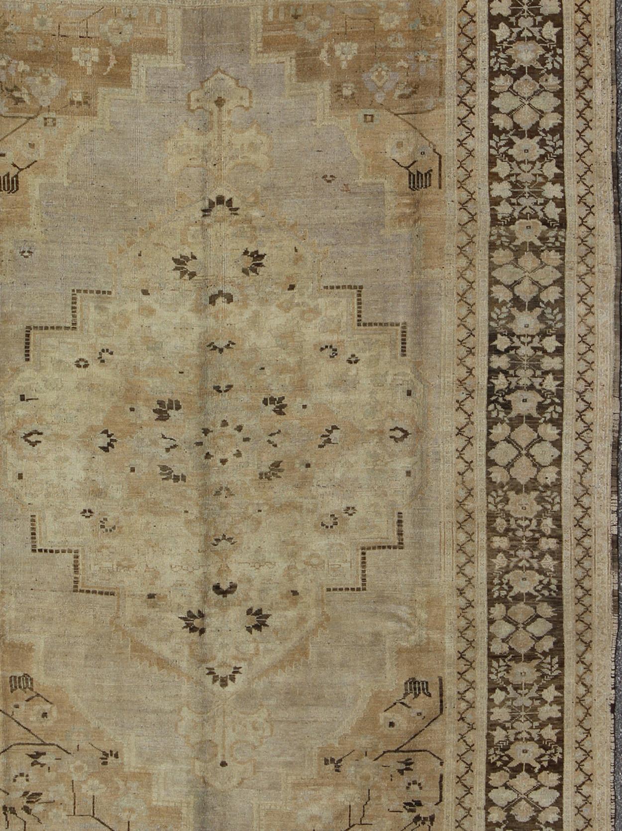 Dieser türkische Oushak im Vintage-Stil aus der Türkei der 1940er Jahre weist eine schokoladenbraune Bordüre mit Blumen und Ranken auf. Das sandfarbene Feld kombiniert Taupe und Hellbraun mit Dunkelbraun und Altweiß in einem großen zentralen