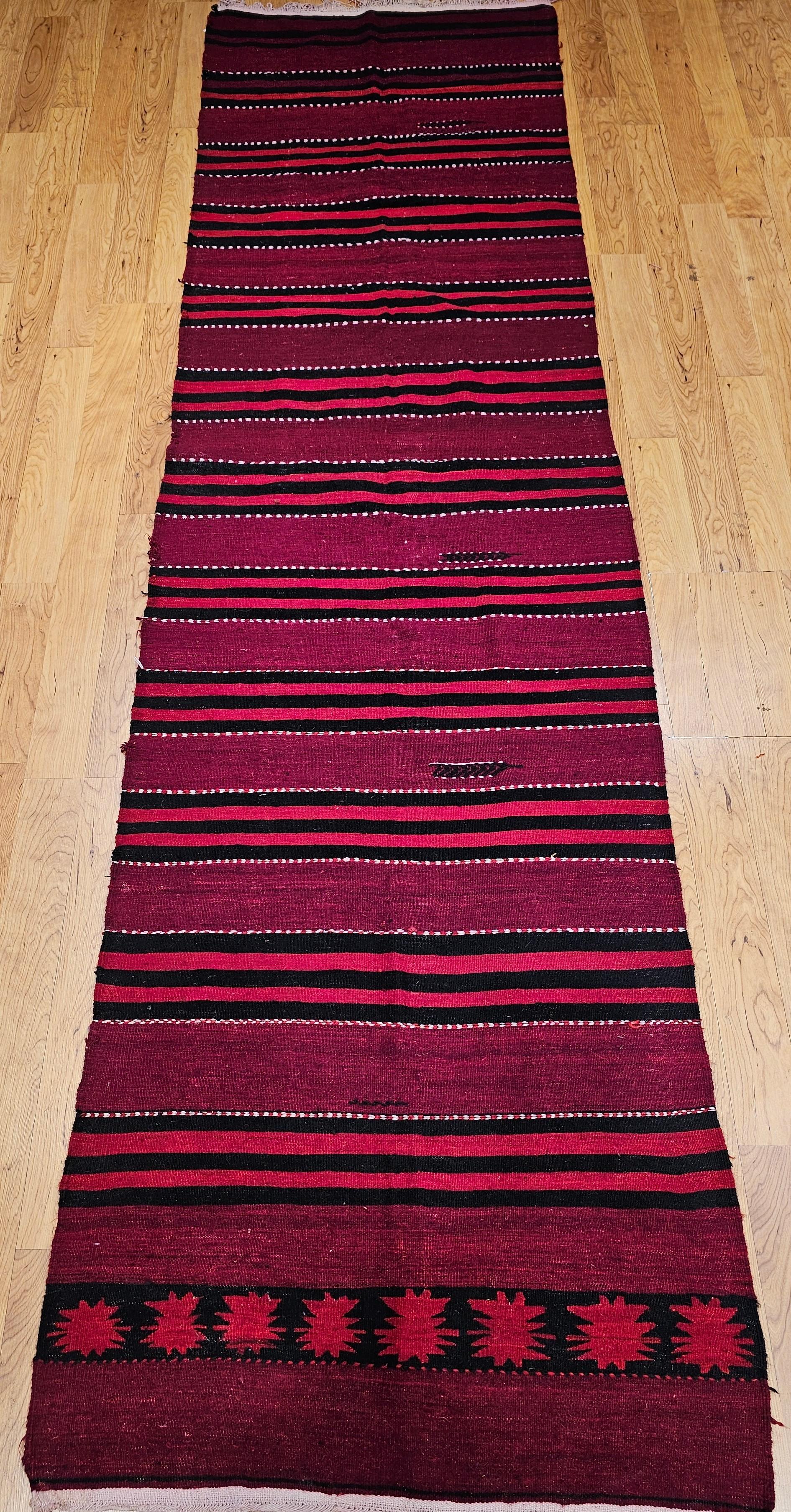 Beautiful and colorful Turkish hand woven kilim runner from the mid 1900s.  The kilim has a stripe pattern design in alternating red and black stripes.    The use of the natural dyes and the gradual tone changes (abrash) adds to the beauty of this