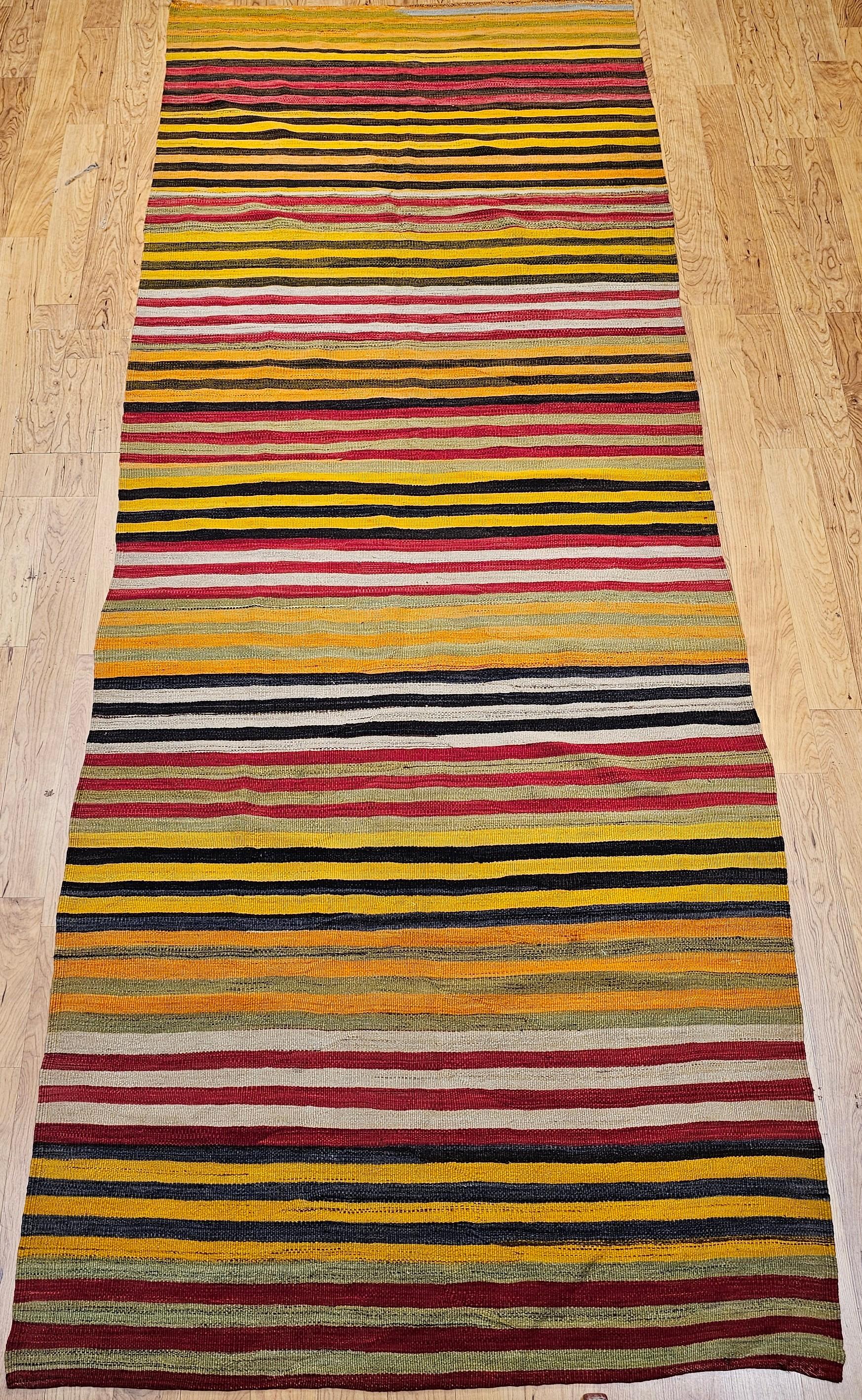 Beautiful and colorful Turkish hand woven kilim wide runner from the mid 1900s.  It has wonderful bright colors of yellow, red, cranberry, tan, navy and blue.    The use of the natural dyes and the gradual tone changes (abrash) adds to the beauty of