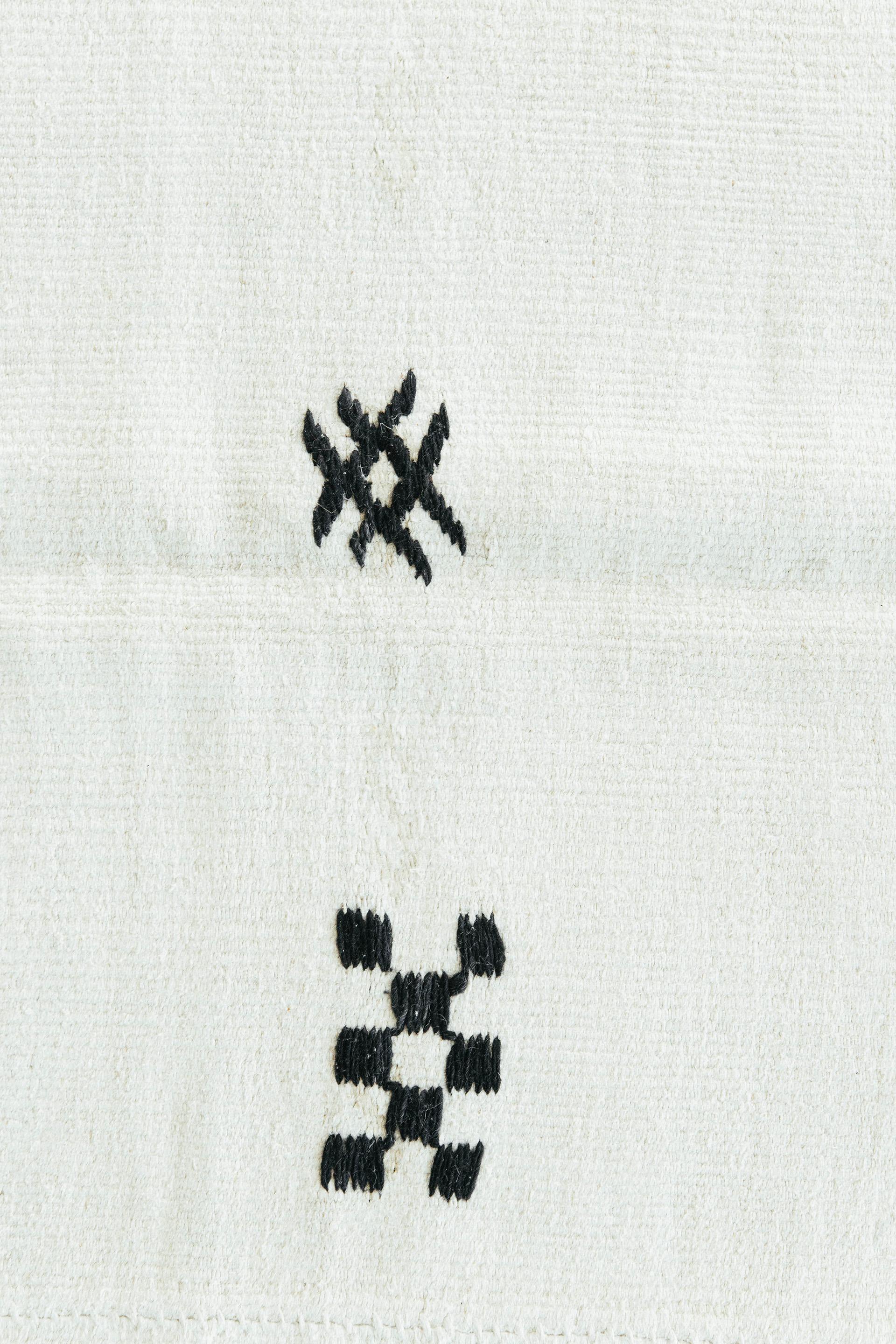 Der perfekte weiße Vintage-Kilim aus türkischem Hanf. Dieses Stück ist aus Hanf gefertigt, der eine sehr interessante Textur erzeugt, die sowohl langlebig als auch einfach zu gestalten ist. Sporadische Stammesmotive sorgen für eine einzigartige und