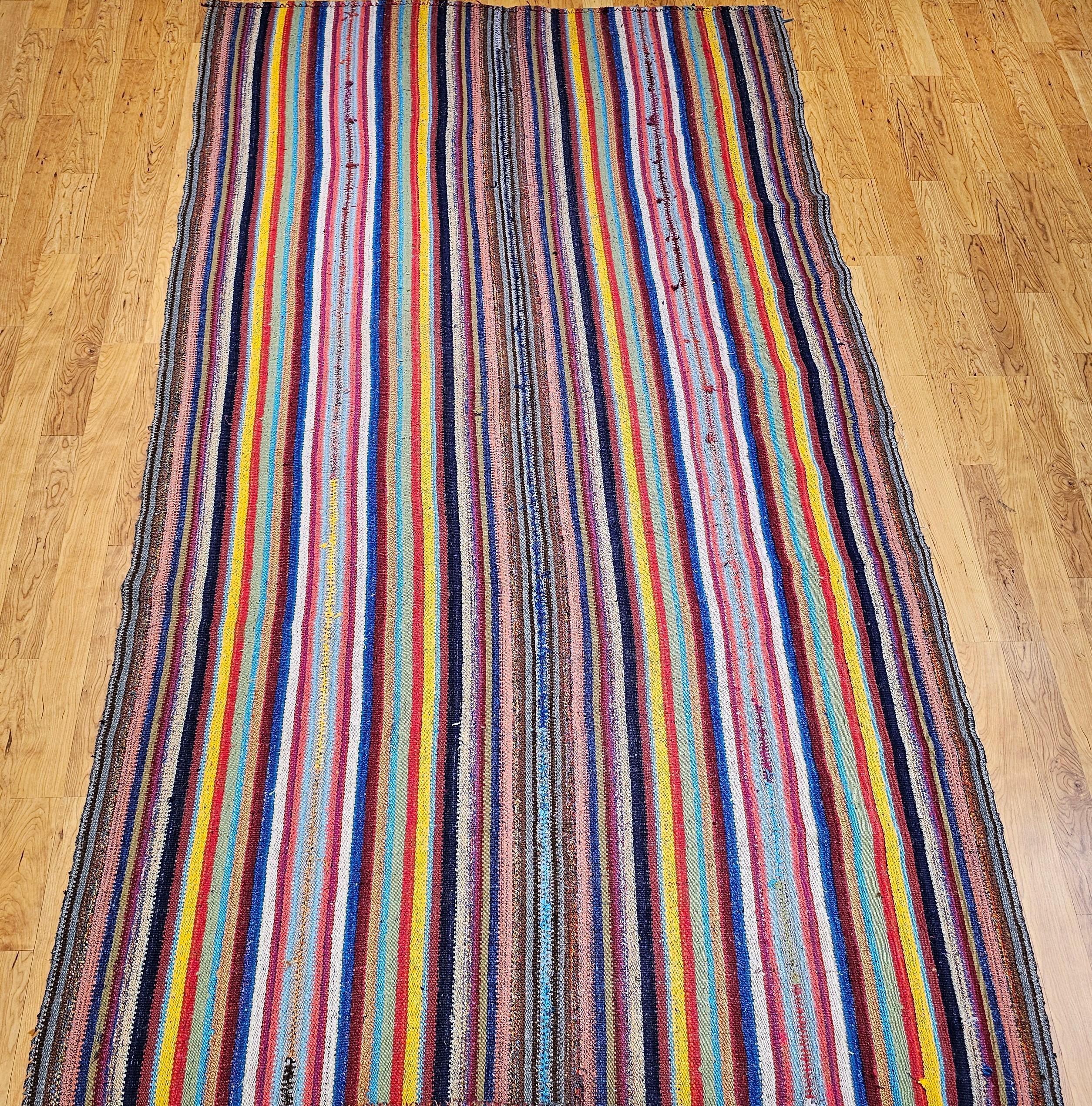 Vintage Turkish Jajim hand woven kilim rug with colorful stripes. This handwoven Jajim Kilim has stripes in multiple colors including blue, green, red, orange, brown, gray, yellow, and purple.  The Jajim kilim was assembled by sewing together 4