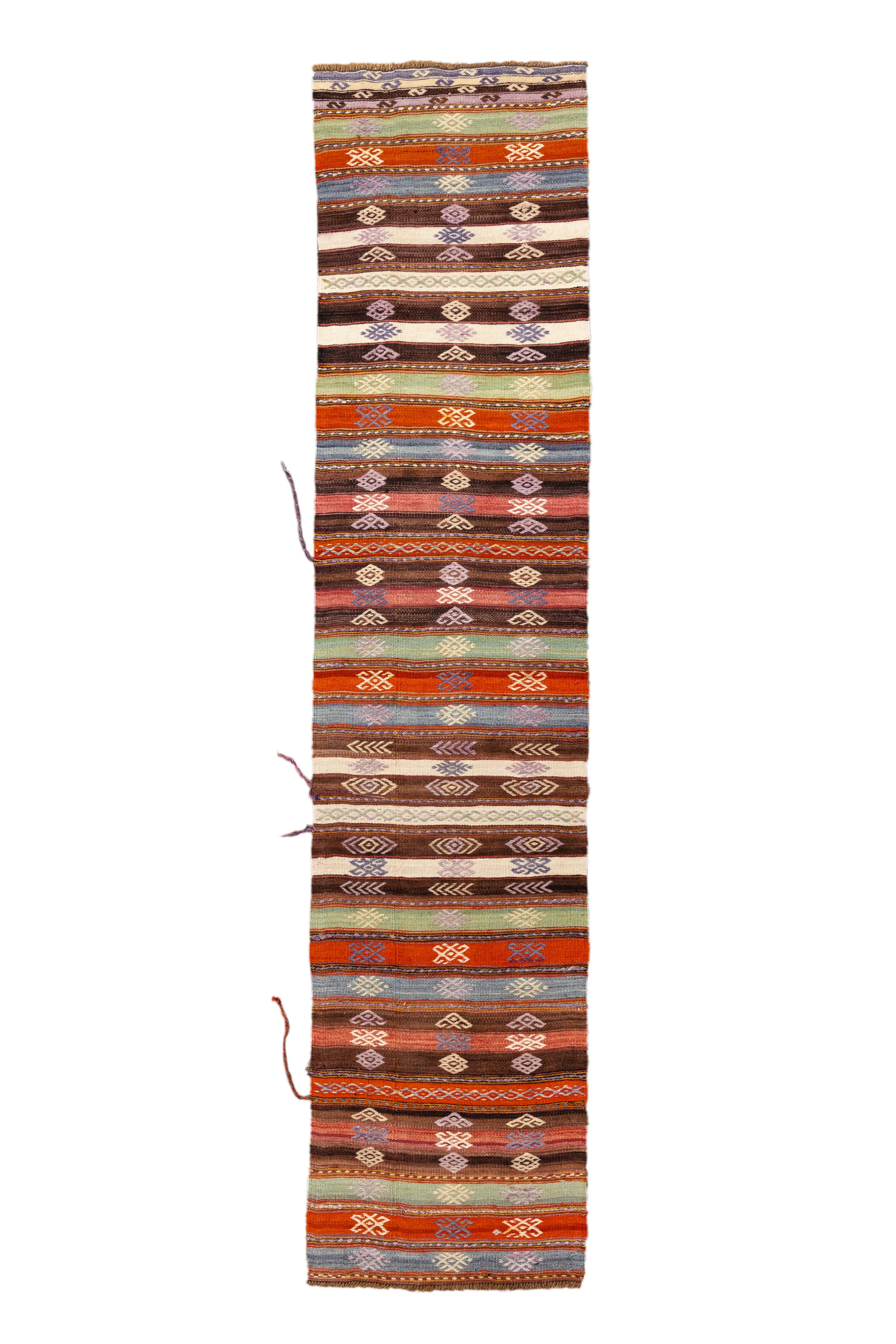 Un runner vintage di Jijim splendidamente sobrio, composto da una tavolozza calda e terrosa con strisce orizzontali alternate ed emblemi tribali. Tessuto in tonalità naturali di terracotta, marrone, marrone, avorio, oliva e lavanda, il disegno è
