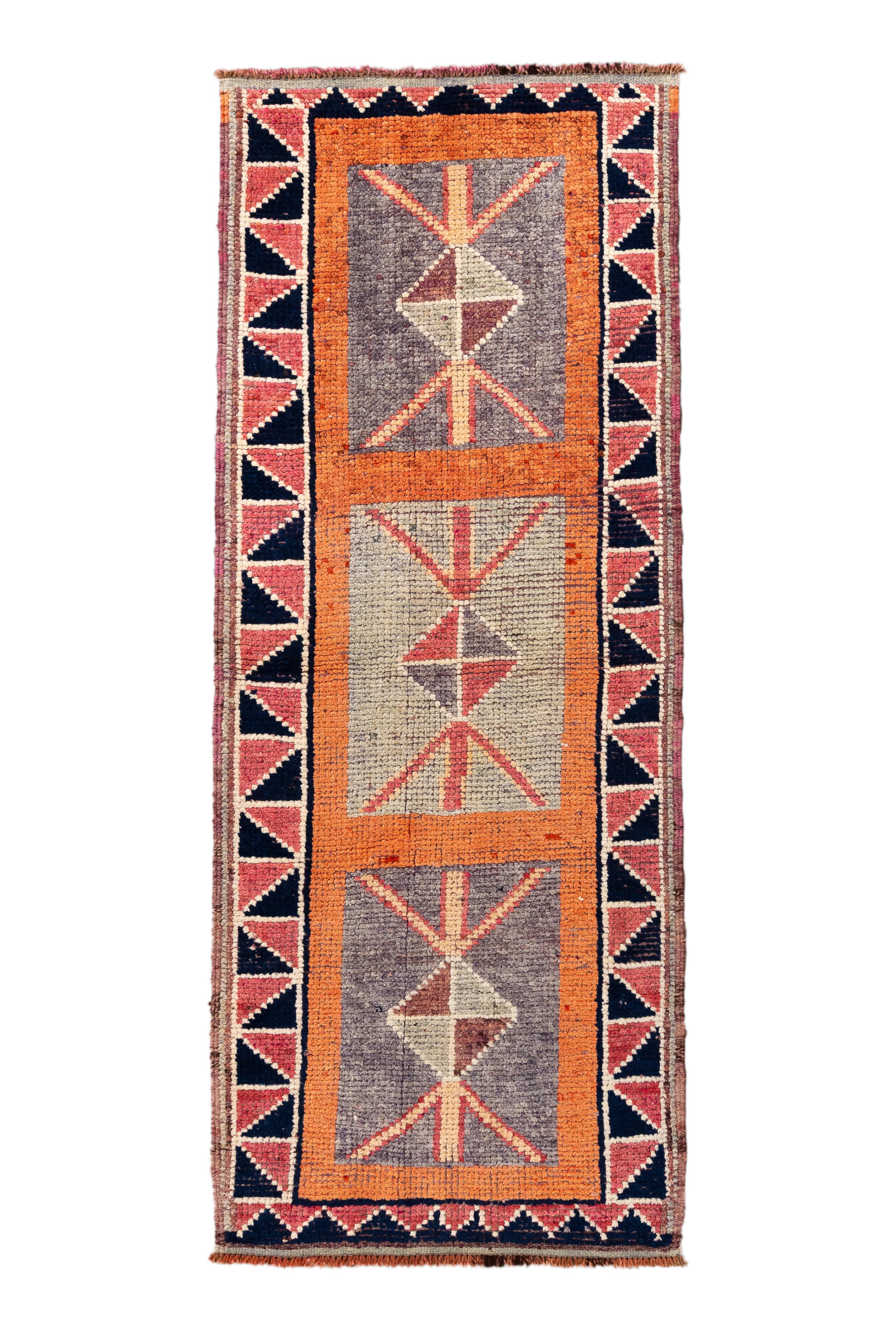 This striking vintage Kars runner showcases a bold and minimalist geometric pattern with three central medallions rendered in earthy neutrals, terracotta, and indigo. Set against a textural field of abrash-dyed wool, the rug is framed by a stepped