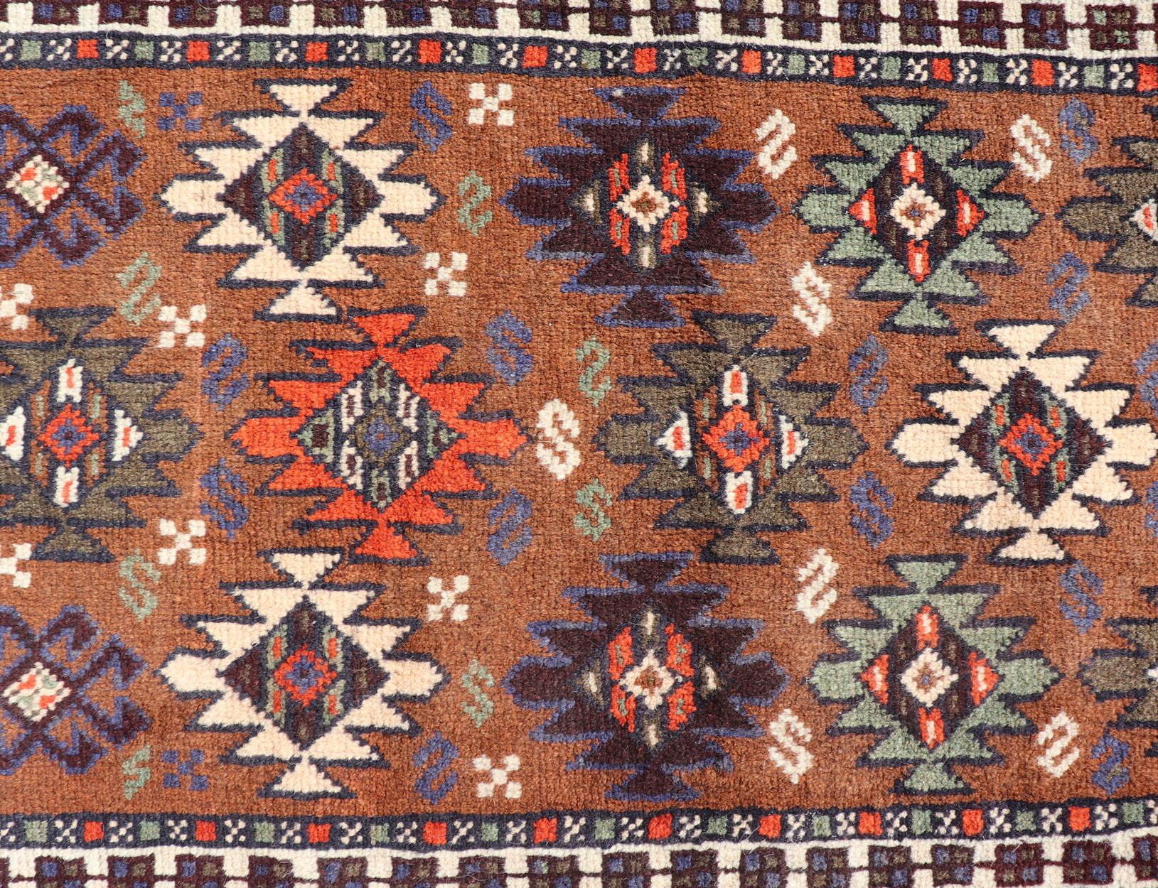 Vieux tapis Kars turc avec motif tribal dans des couleurs orange-marron. Keivan Woven Arts / tapis EMB-9663-P13552, pays d'origine / type : Turquie / Oushak, vers le milieu du 20ème siècle.

Ce chemin de table vintage présente un assortiment de