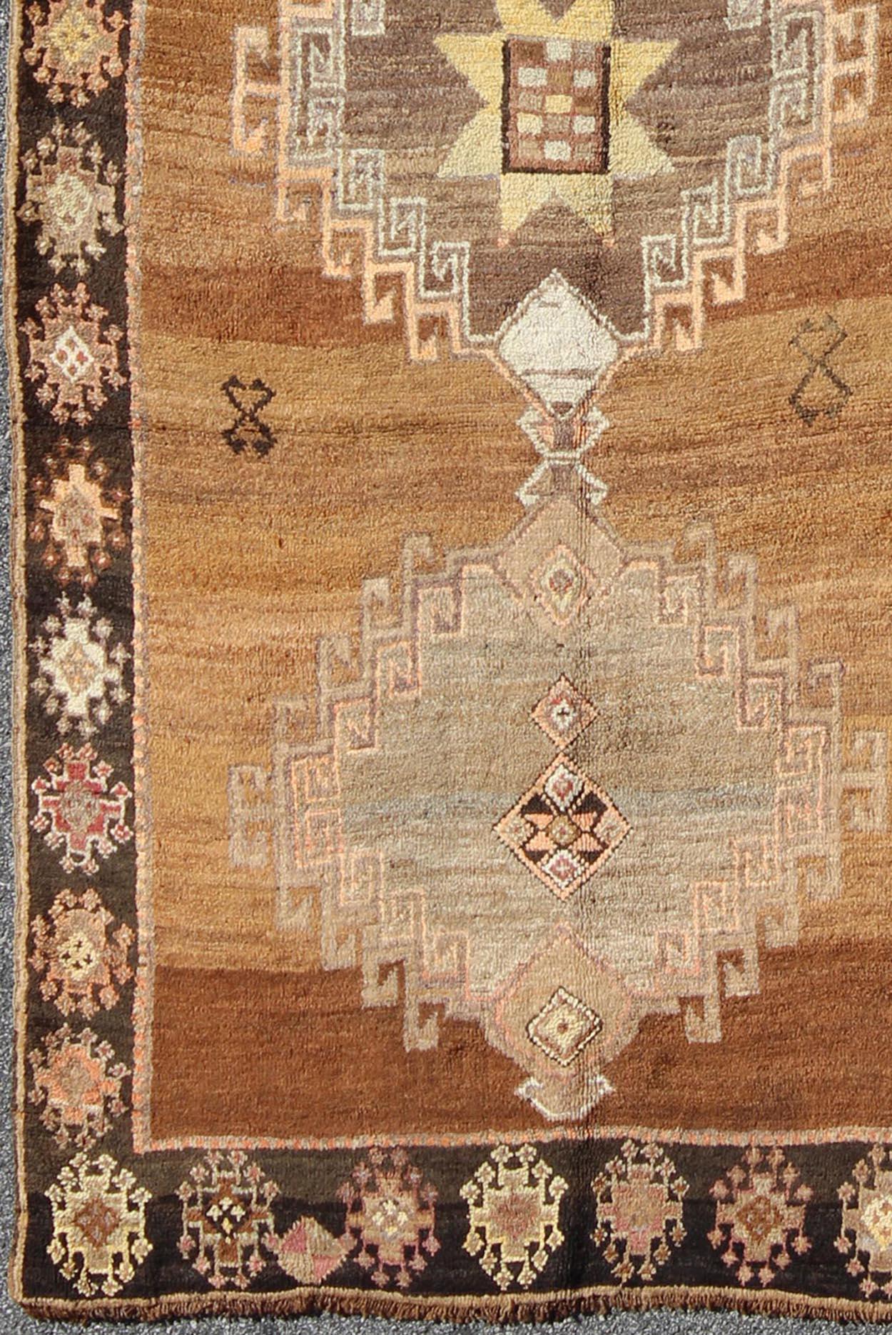Measures: 4'6 x 10'11

This Kars Oushak features a triple center medallion with an overall geometric design scheme. The camel colored background homes three large tribal medallions, rendered in shades of taupe. The border has geometric repeating