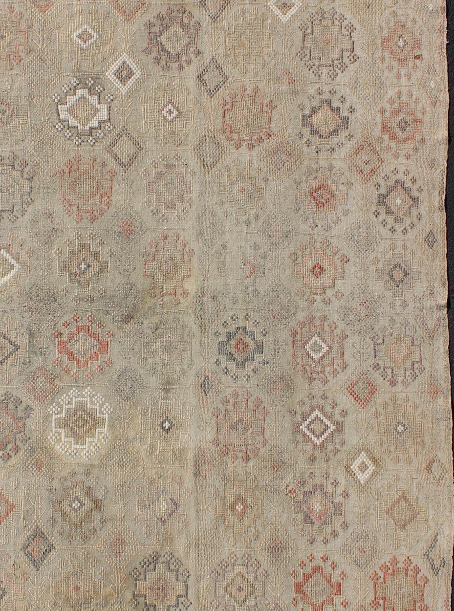 Measures 4'7 x 8'0 

This rug features an asymmetrical design of tribal crests decorating the light blue-grey field. The crests are rendered in varying muted shades including brown, blue, salmon, fleshy creams, red, ivory and ebony. With simple