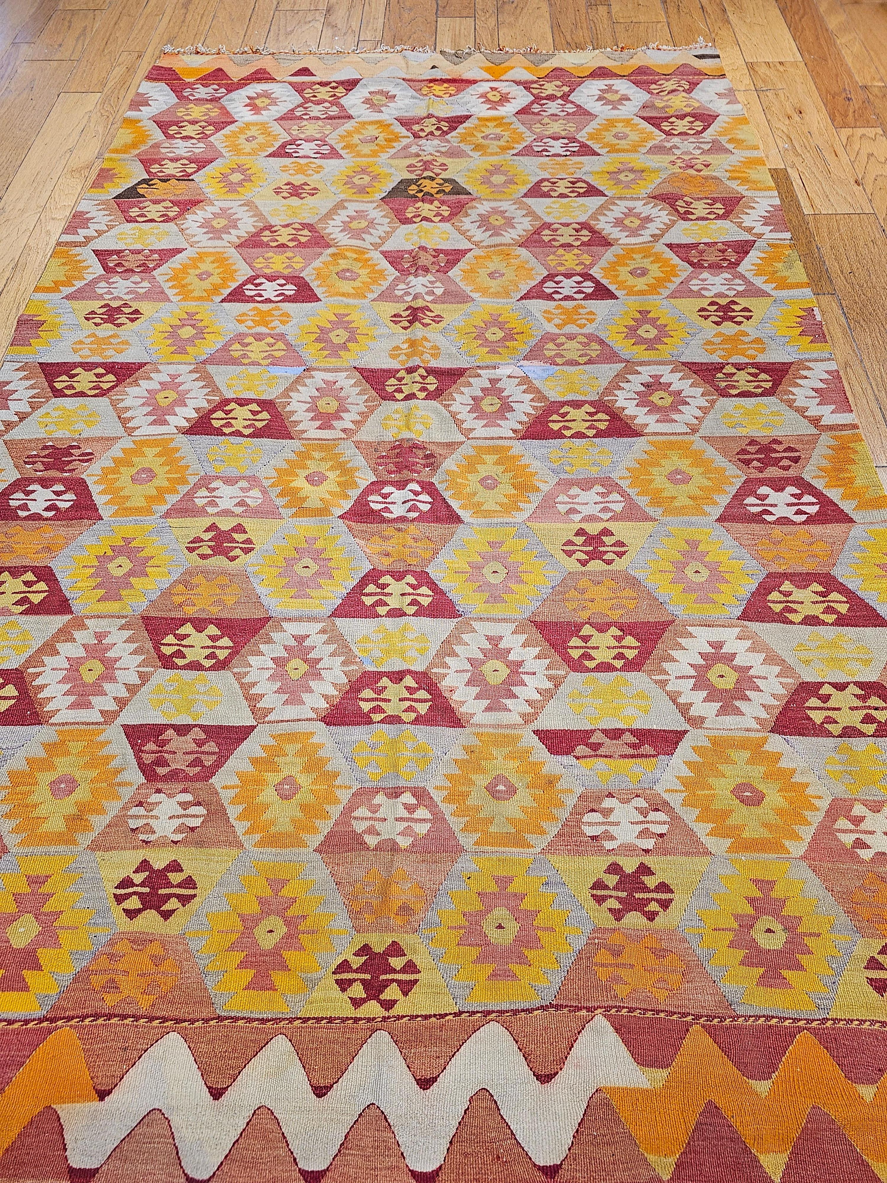 Vintage room-size Turkish kilim from the 2nd quarter of the 1900s in an all over geometric pattern in autumn colors of red, orange, yellow, ivory and gray.  The color scheme in this kilim are warm Southwestern colors and the beautiful colors of the