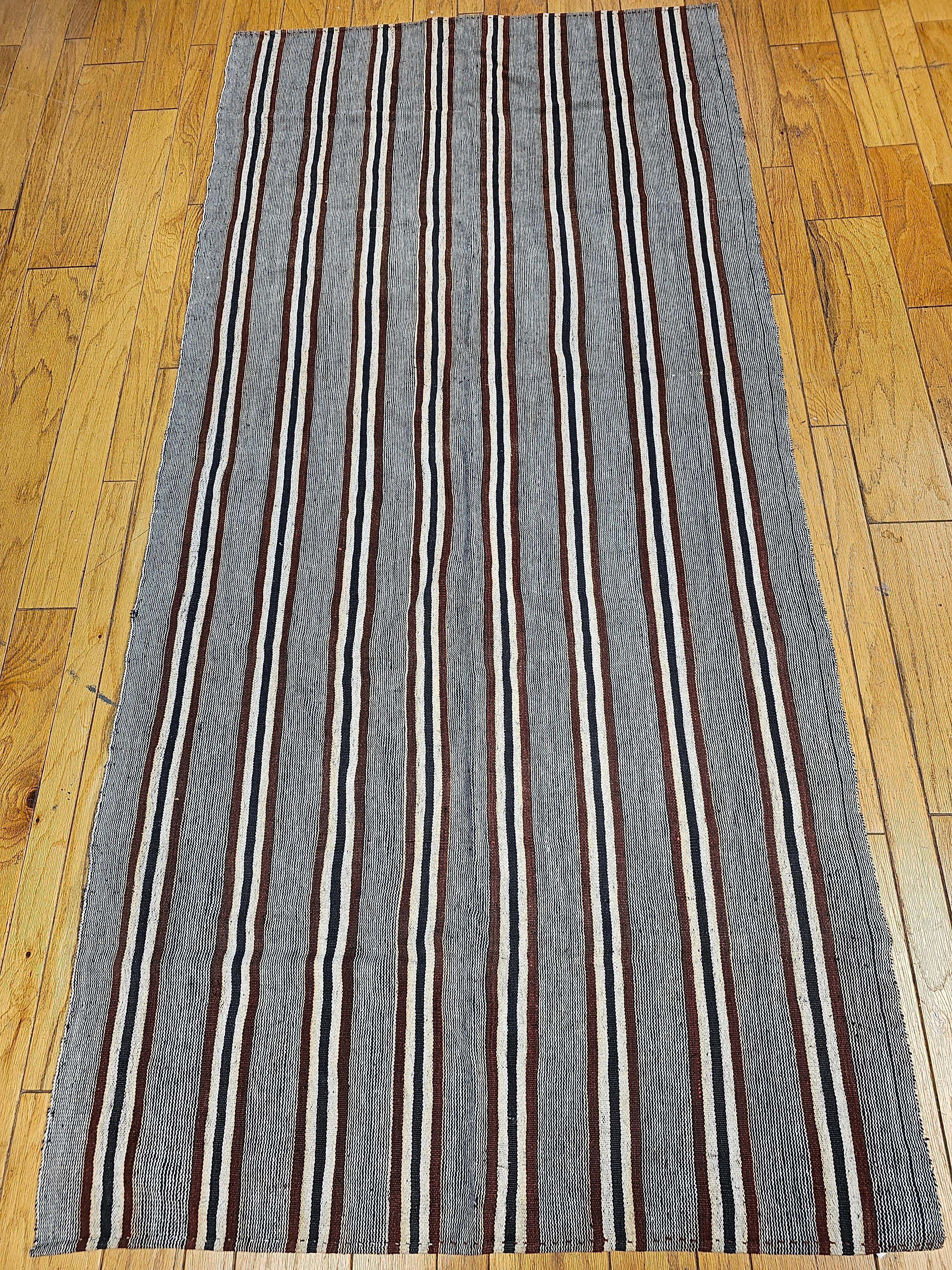  Modern style vintage Turkish Kilim flat-weave rug in earth tone colored stripes. This handwoven wool vintage Turkish Kilim has a gray background with vertical lines stripes in multiple colors including maroon, white, black dividing the field. The