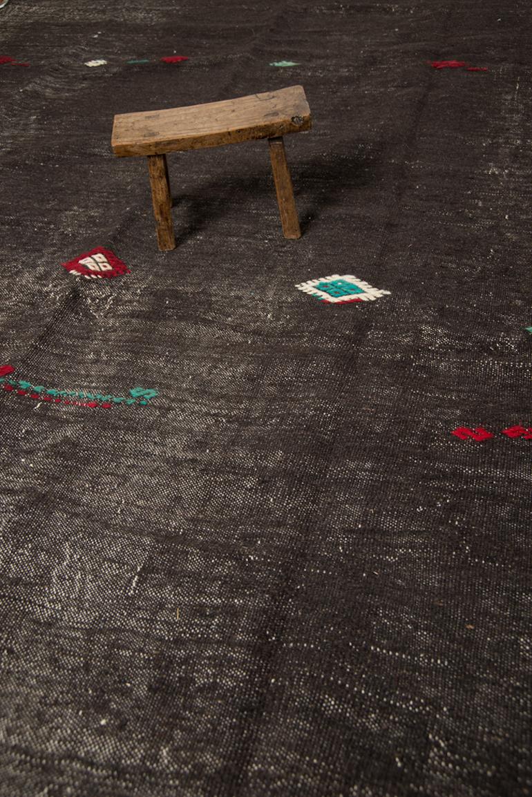 This vintage Kilim is simple in design yet so elegant with its deep dark brown and just a few cleverly placed hand-embroidered tribal motifs. This design captures both, elegance and raw beauty. Just unique and authentic. The most remarkable
