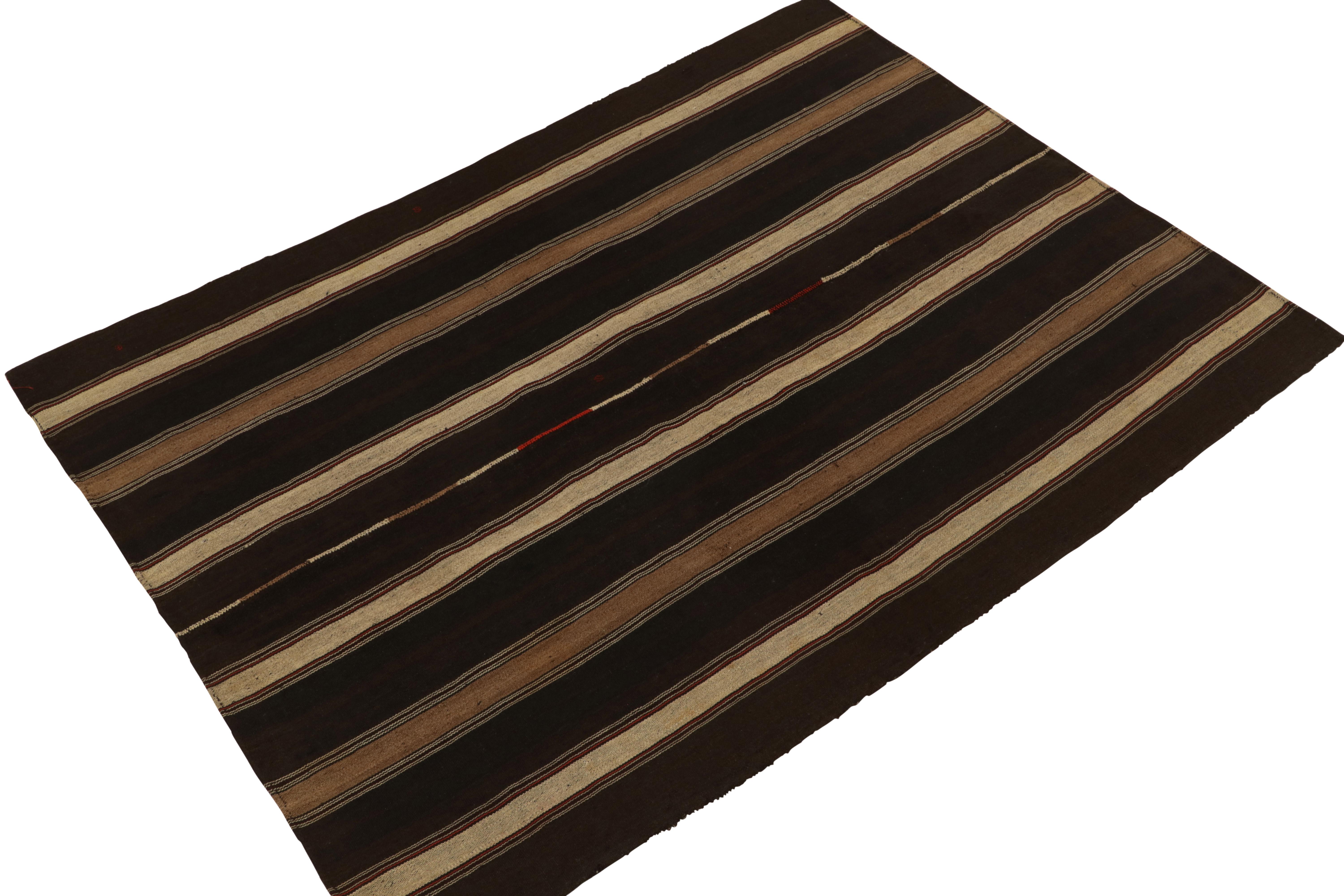 Handwoven in wool, a 5x7 vintage Turkish kilim rug originating circa 1950-1960, connoting a distinctive mid-century panelwoven style. The technique creates a forgiving series of stripes in beige and brown with red accents, perfectly reflected on the