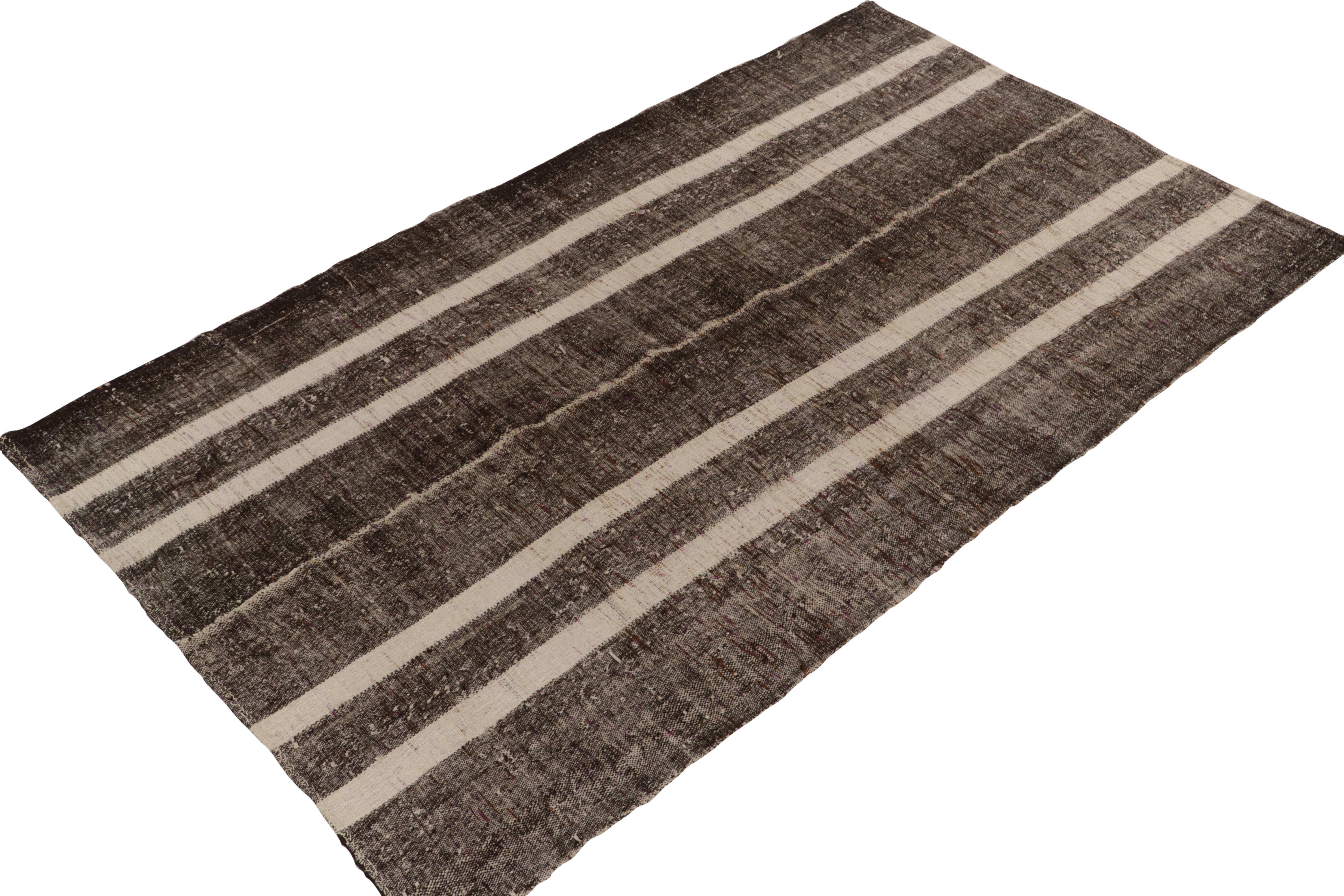 Originaire de 1950-1960, un tapis kilim vintage 6x10 de Turquie. Tissé à la main en laine avec la technique du tissage à panneaux, le design simple bénéficie d'un jeu neutre de beige-brun avec un élément blanc et noir salé dans les stries. Une