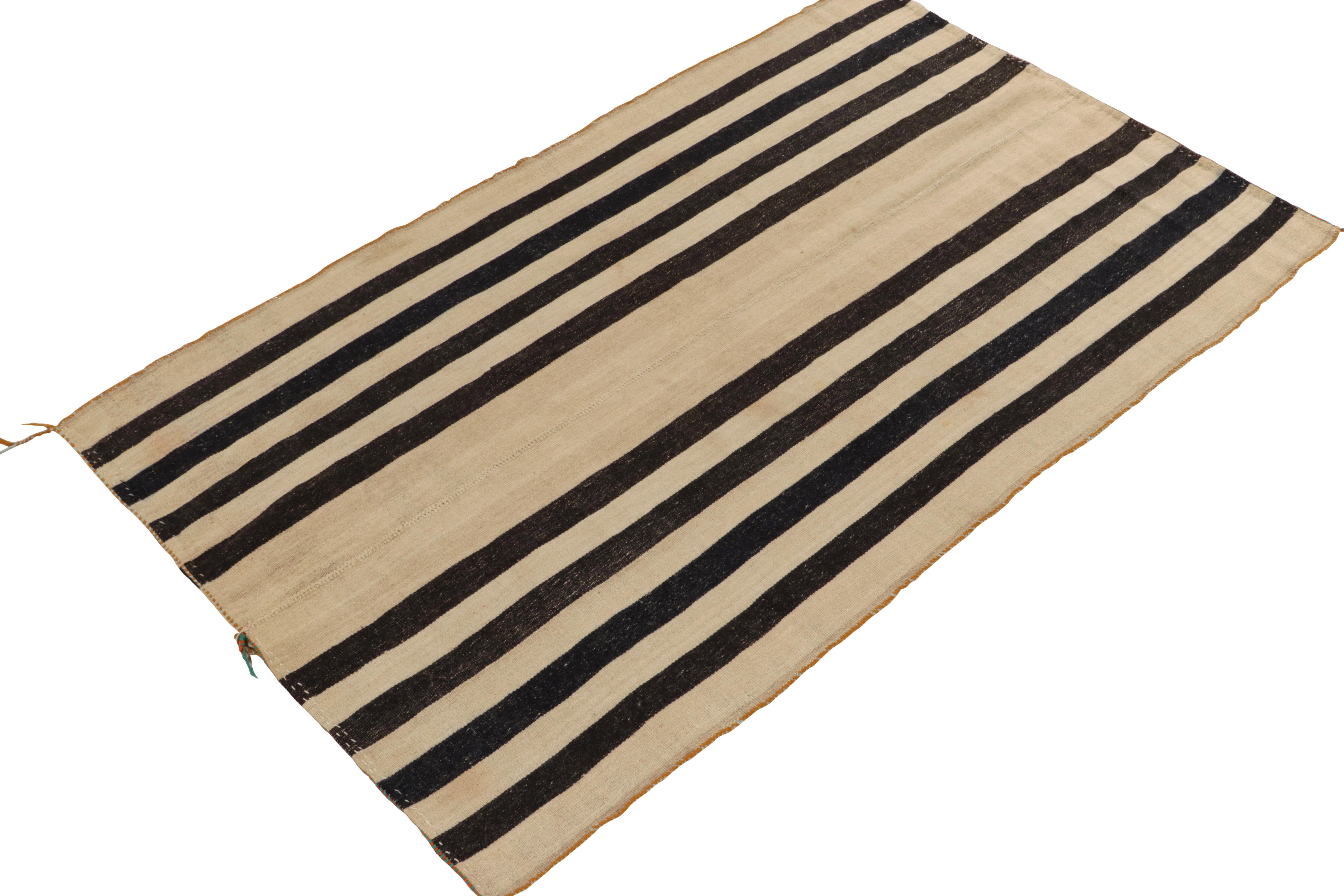 Originaire de 1950-1960, un tapis kilim vintage 5x8 de Turquie. Tissé à la main en laine avec la technique du tissage à panneaux, le design simple bénéficie d'un jeu neutre de beige-brun avec des rayures noires, complété par de légers éléments de