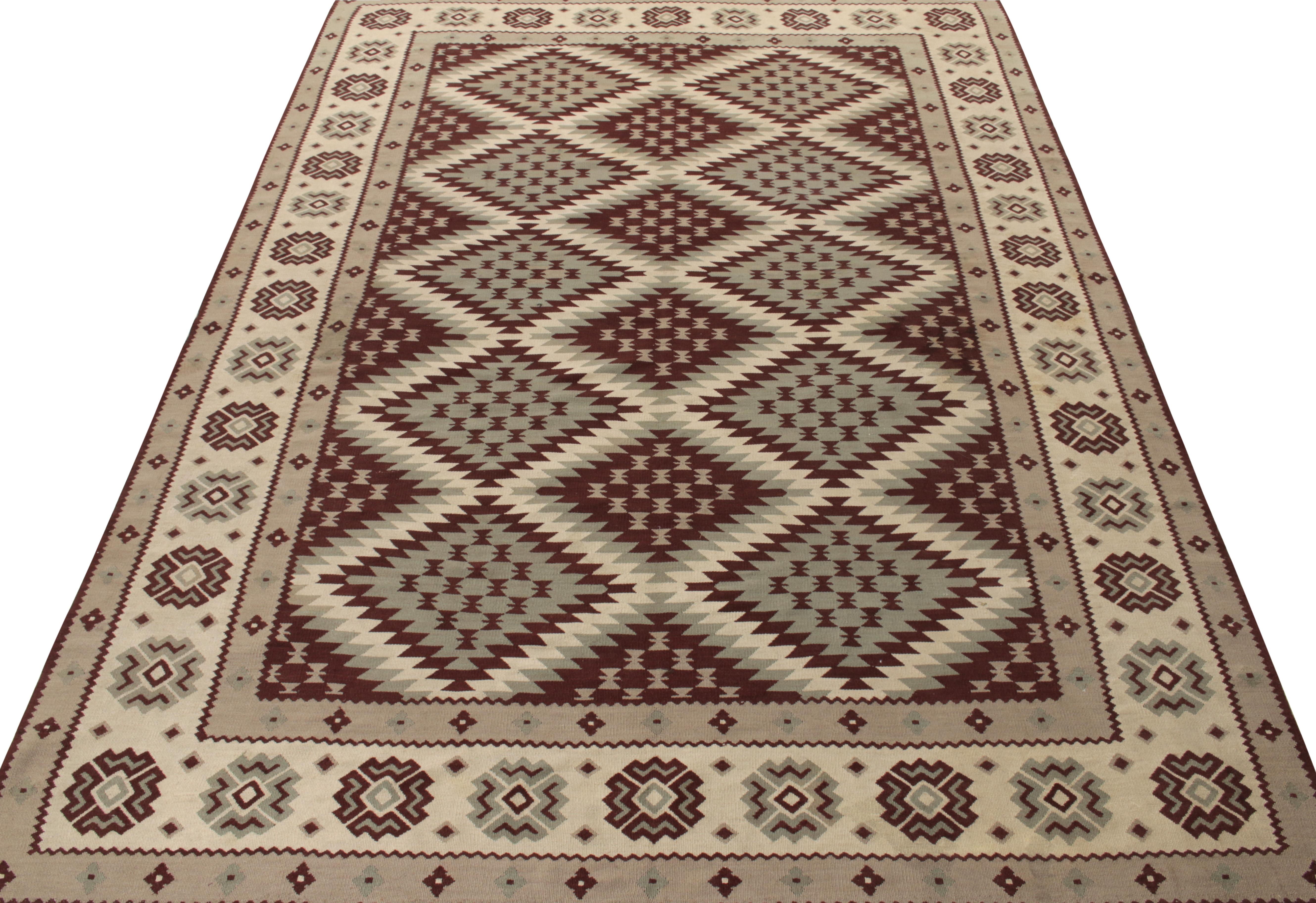 Originating from Turkey circa 1950-1960, a sharp vintage kilim rug featuring a neat geometric pattern with tribal motifs in lava grey, creamy off white and mature brown accents. Bearing Balkan influence, a 6x9 collectible thriving in excellent