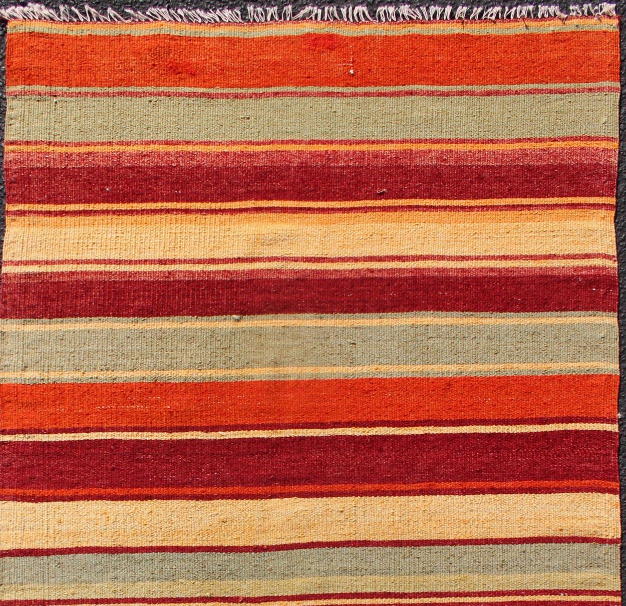 Turkish Kilim runner with stripes in red, green, yellow, orange, rug TU-NED-606, country of origin / type: Turkey / Kilim, circa mid-20th century

Woven during the mid-20th century in Turkey, this designer Kilim is decorated with a horizontal