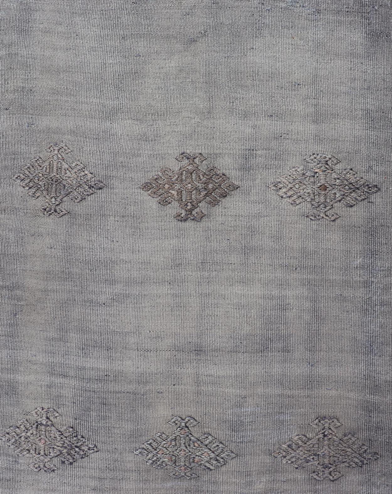 Maße: 2'4 x 9'9 Dieser türkische Kilim-Läufer im Vintage-Stil bietet mit seiner gedeckten Farbpalette und den komplizierten geometrischen Motiven eine raffinierte Eleganz. Der Läufer wird von sanften Grautönen dominiert und ist mit einer Reihe fein